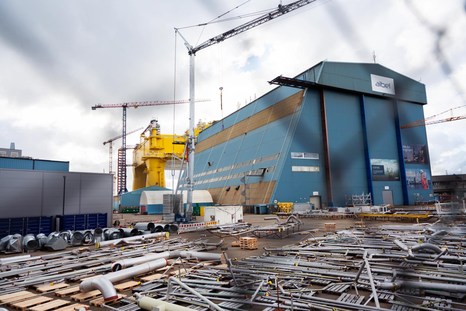 Blue assembly building and yellow offshore wind substation at a Norwegian yard