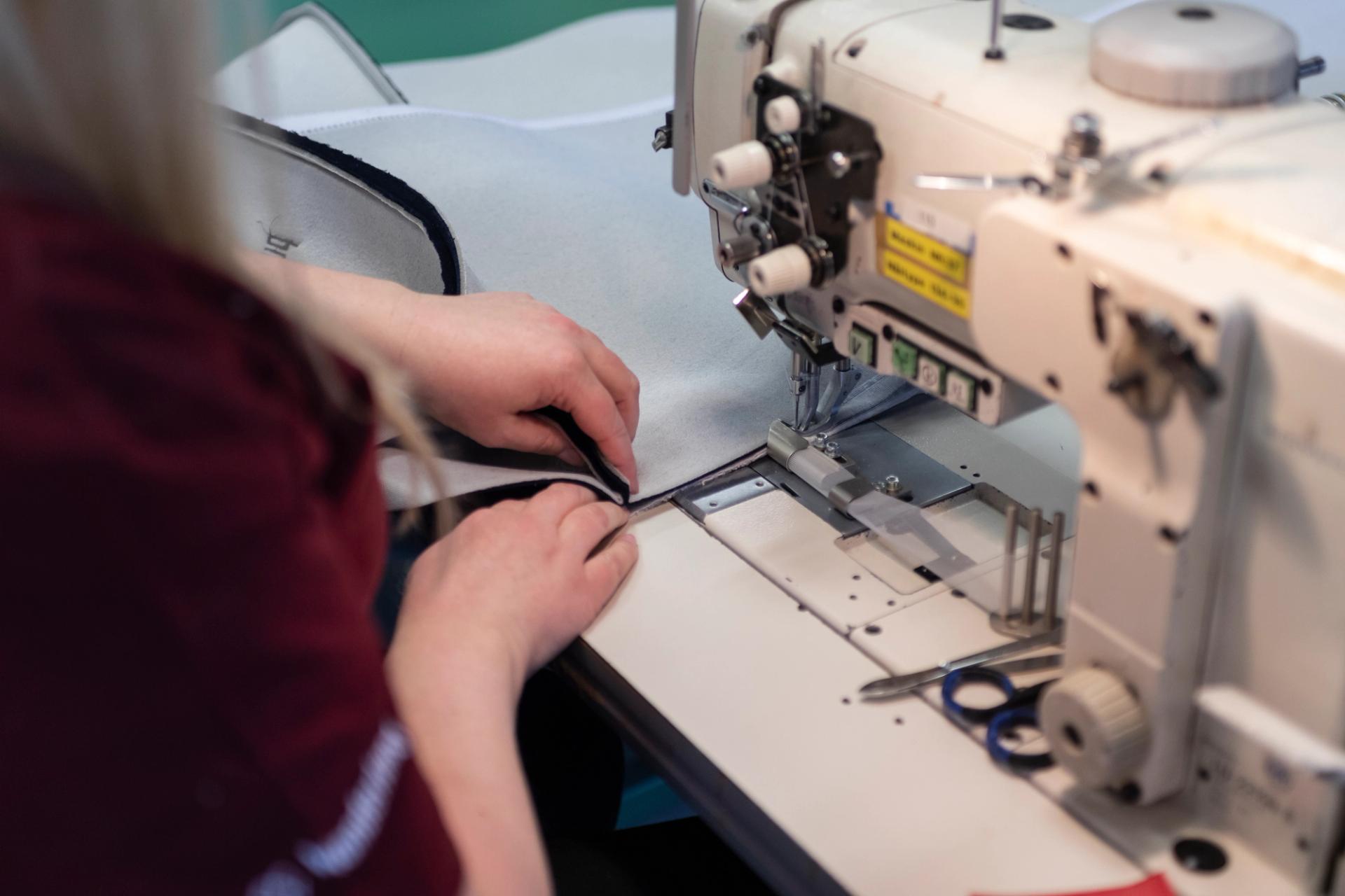 A woman sewing fabric for a bed.
