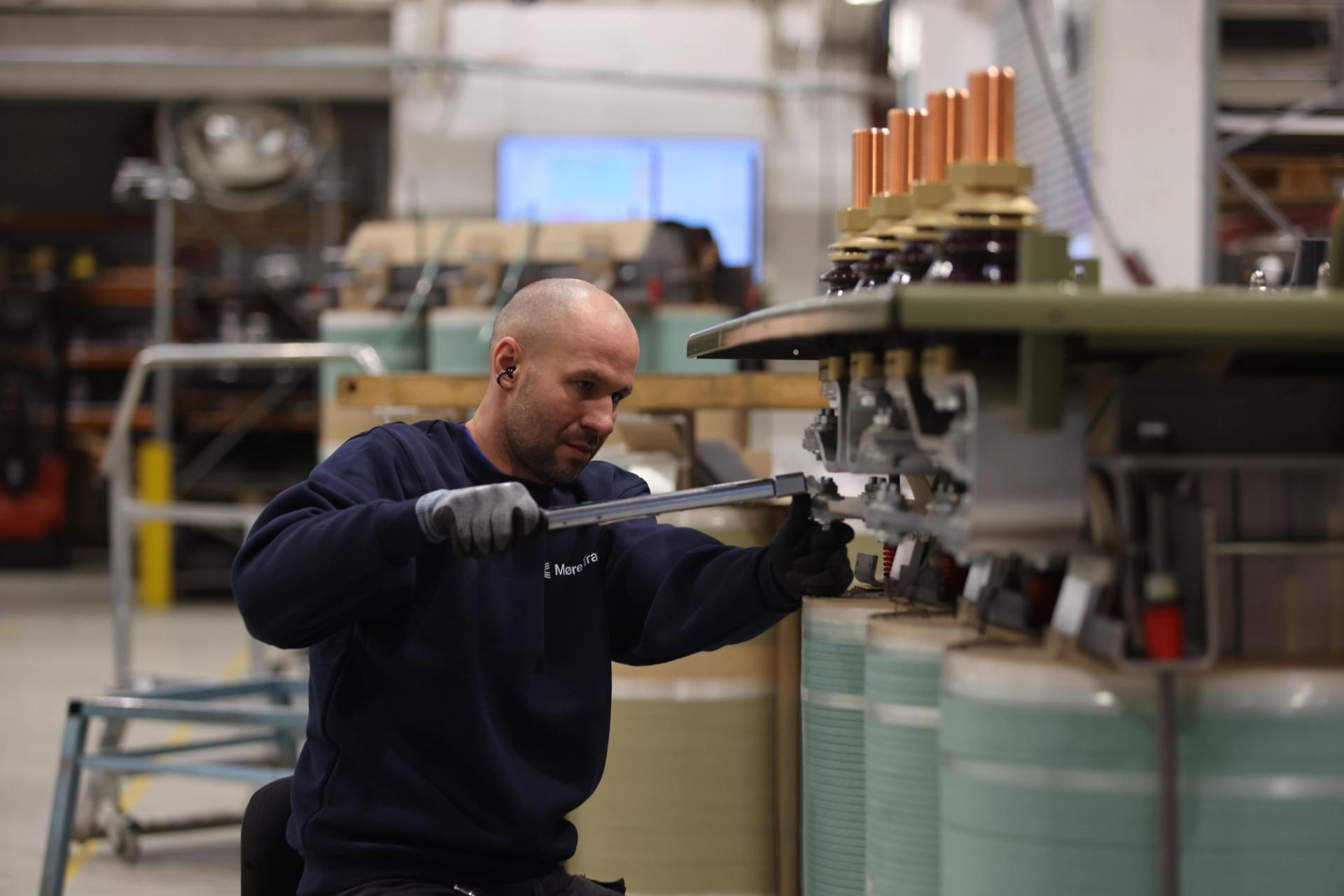 man in a blue jumpsuit with a big wrench