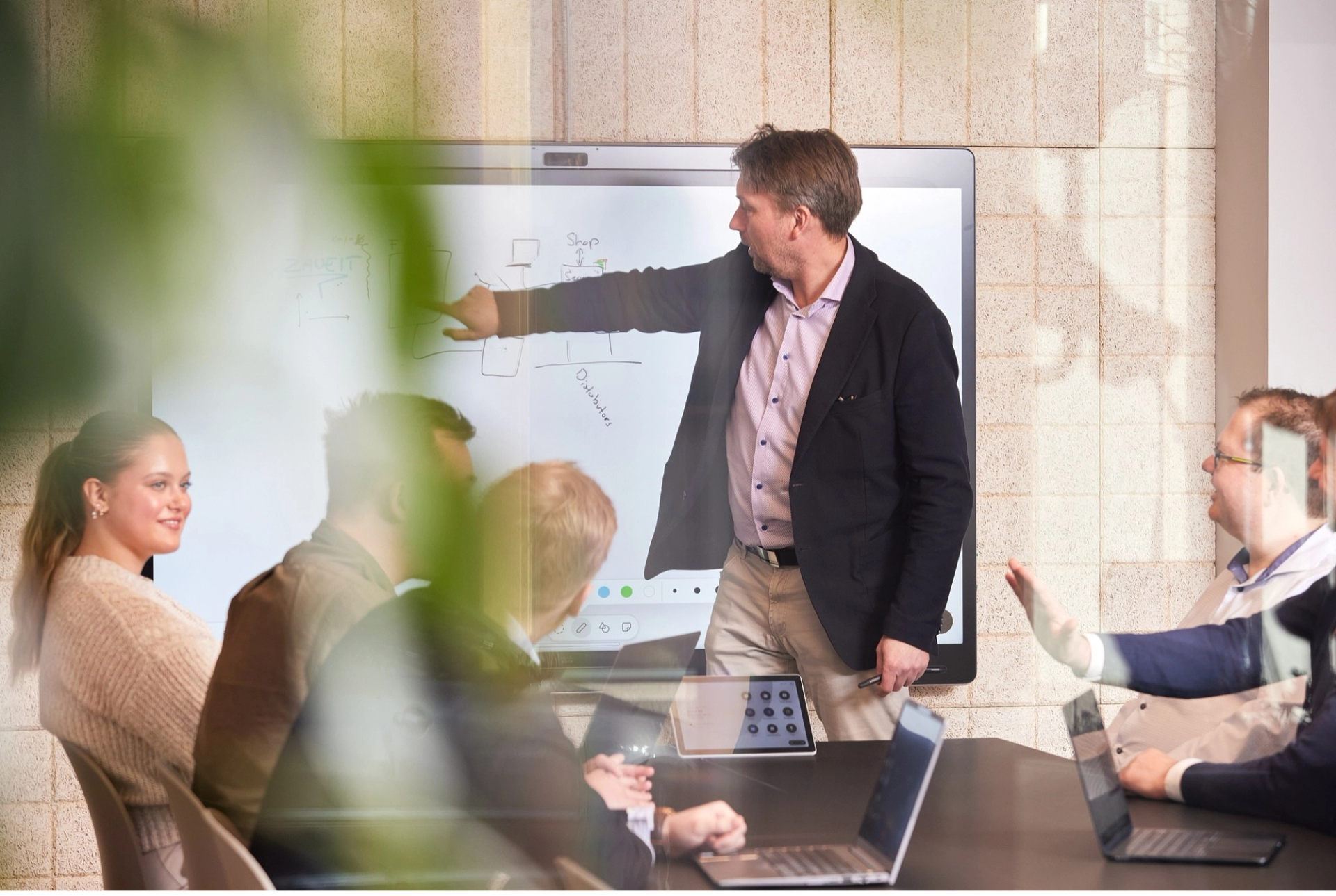 A group of people looking at the shared screen and looking at the man talking.