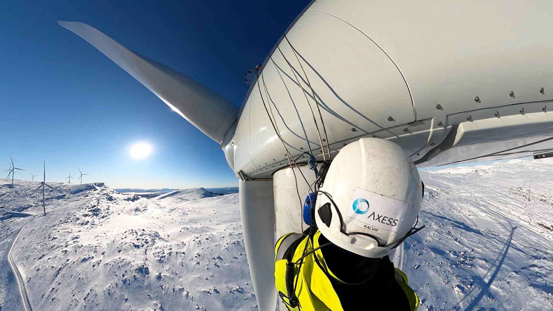 Worker in a white helmet at the top of a wind turbine