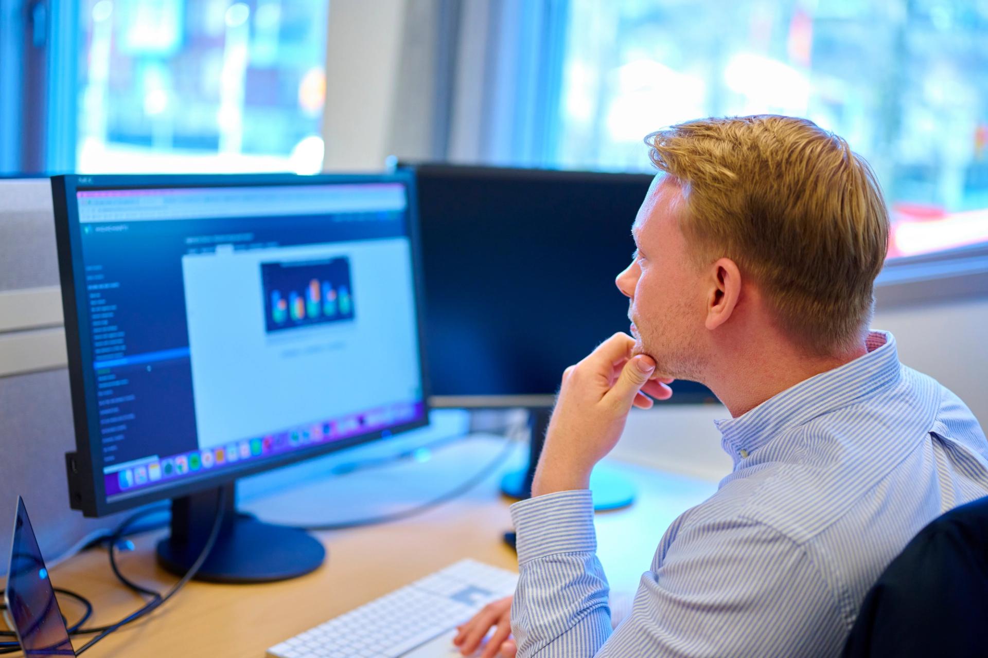 Blond man in a blue shirt looking at a computer screen