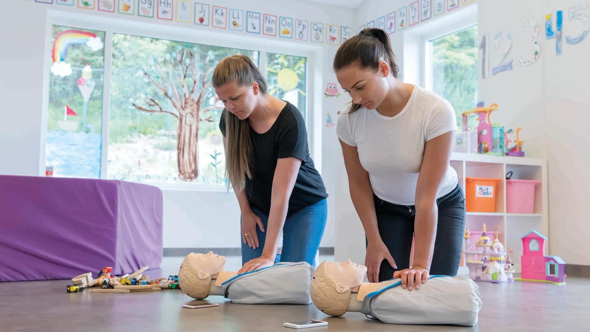 Two women practicing CPR on dummies