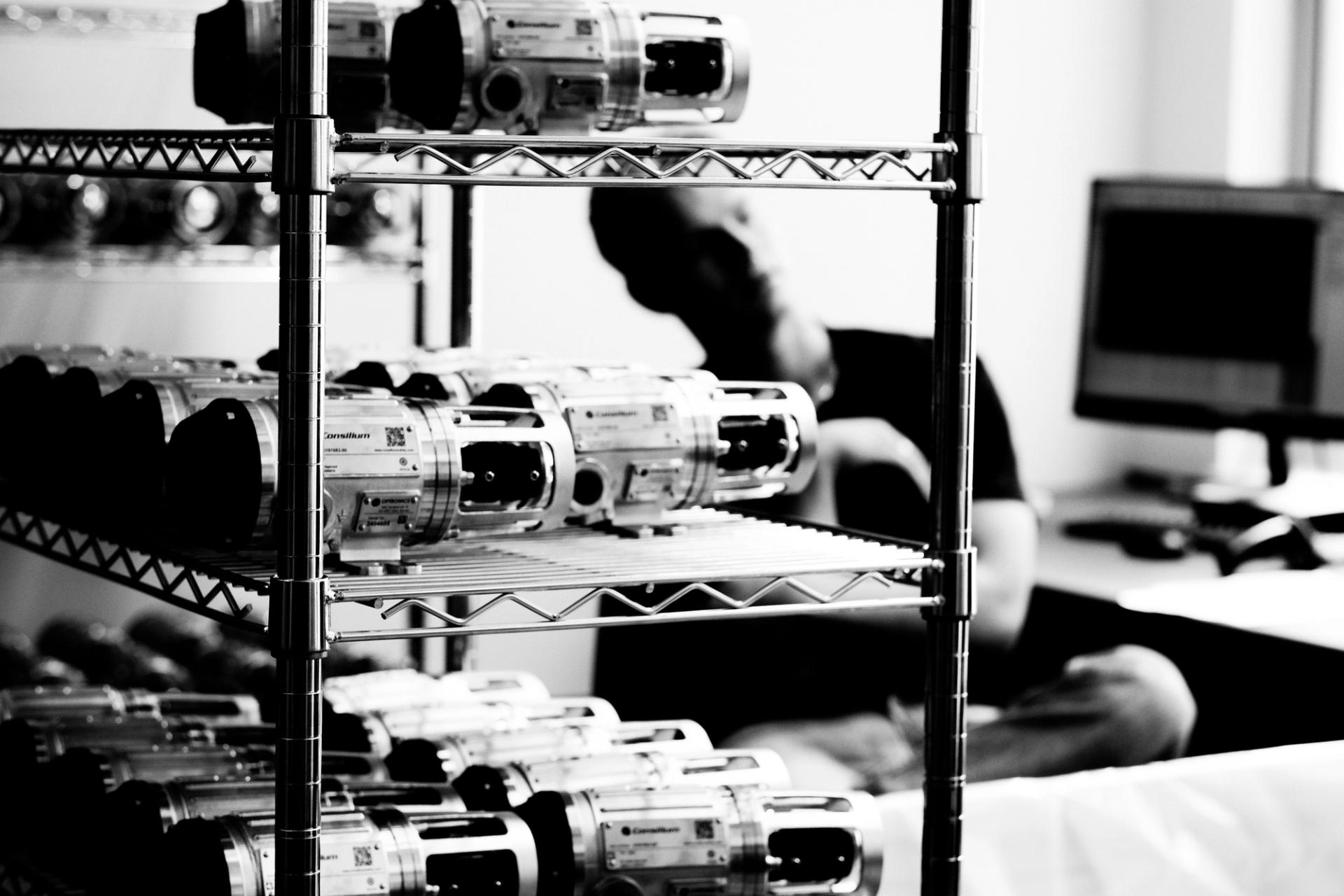 Cylindrical optronic sensor units on a lab shelving rack