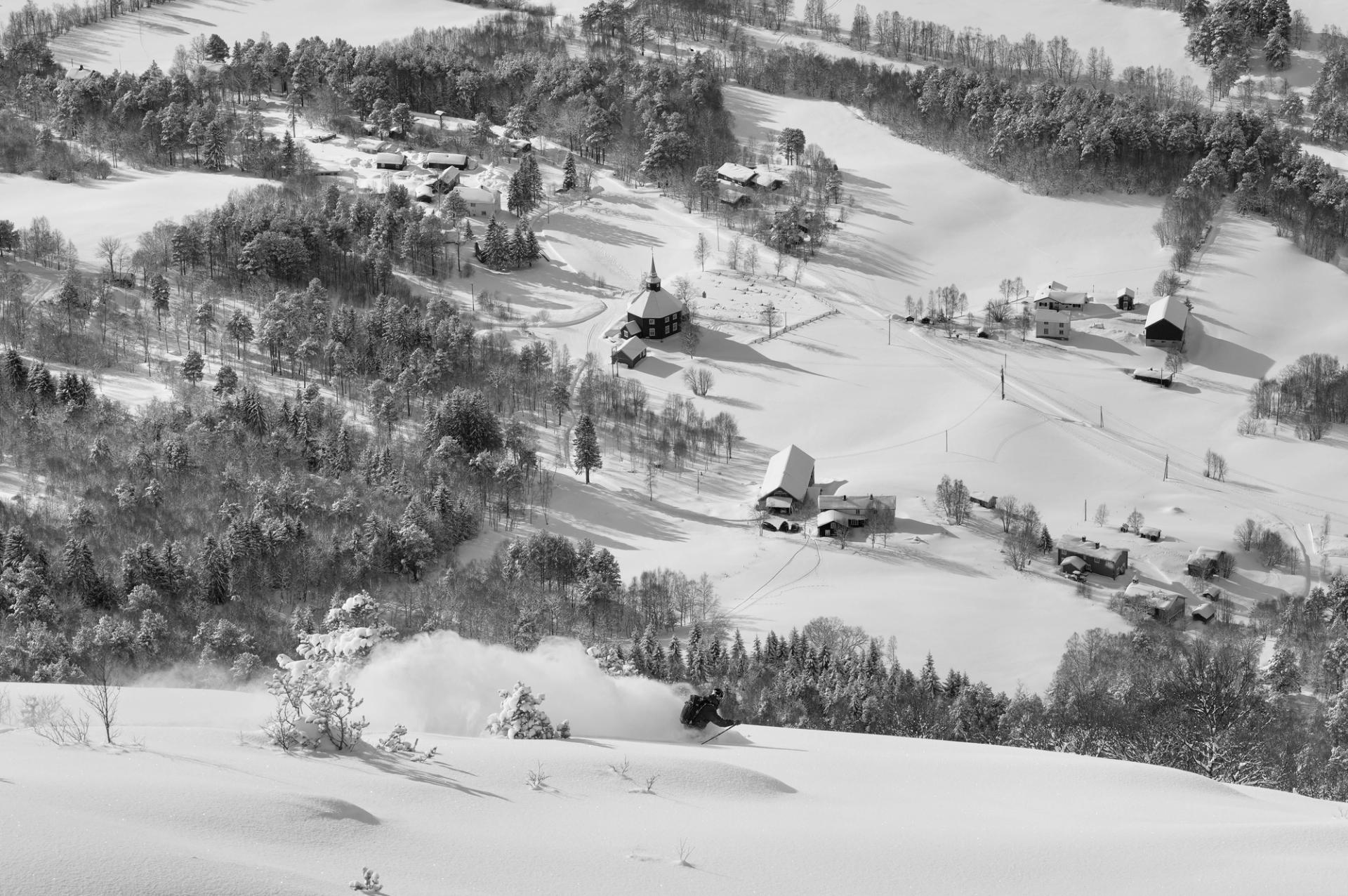 A picture of EVI Ski factory in the distance, with the snow covering the houses and nature.