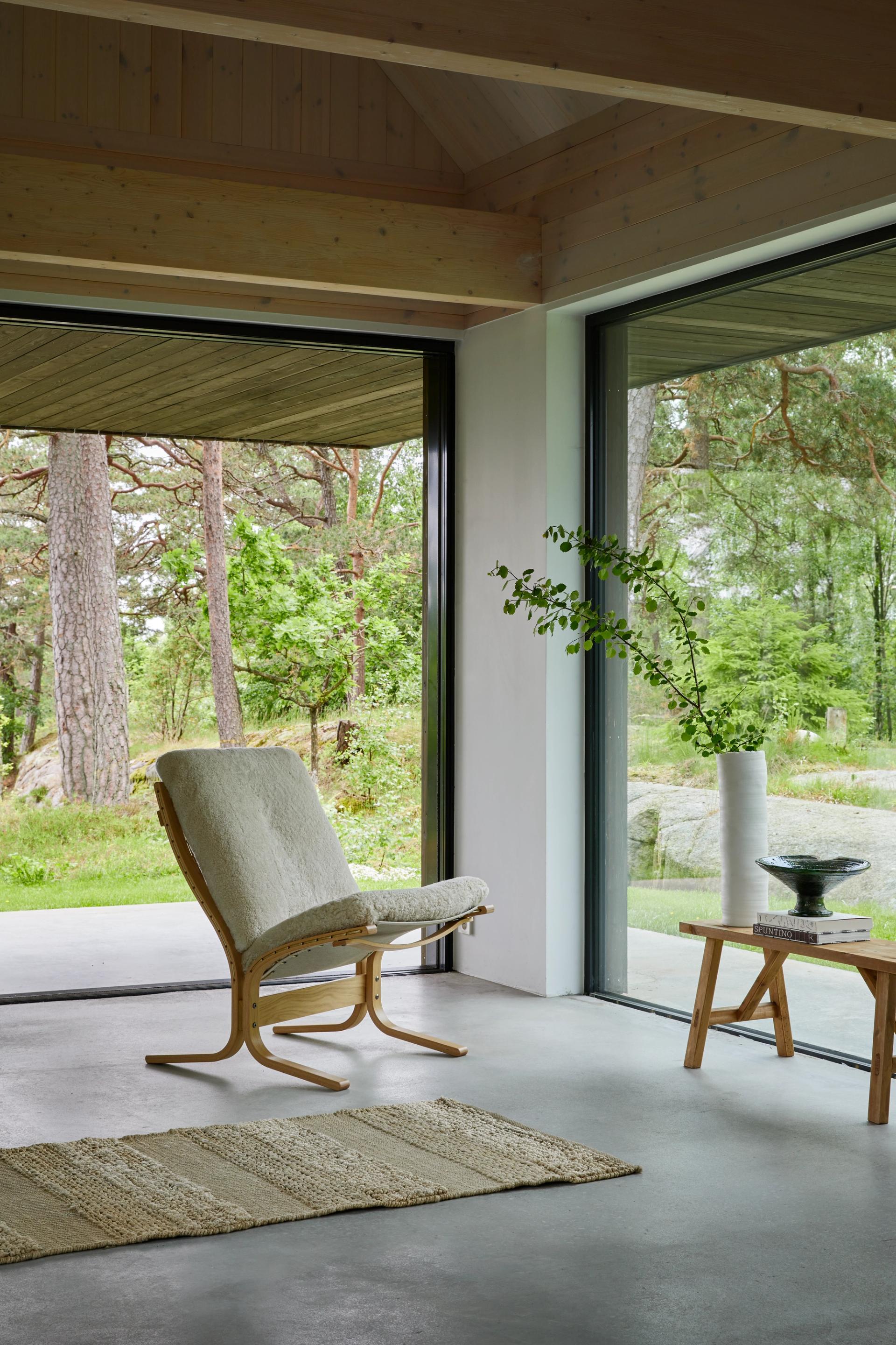 A white chair in a open og light living room with big windows.