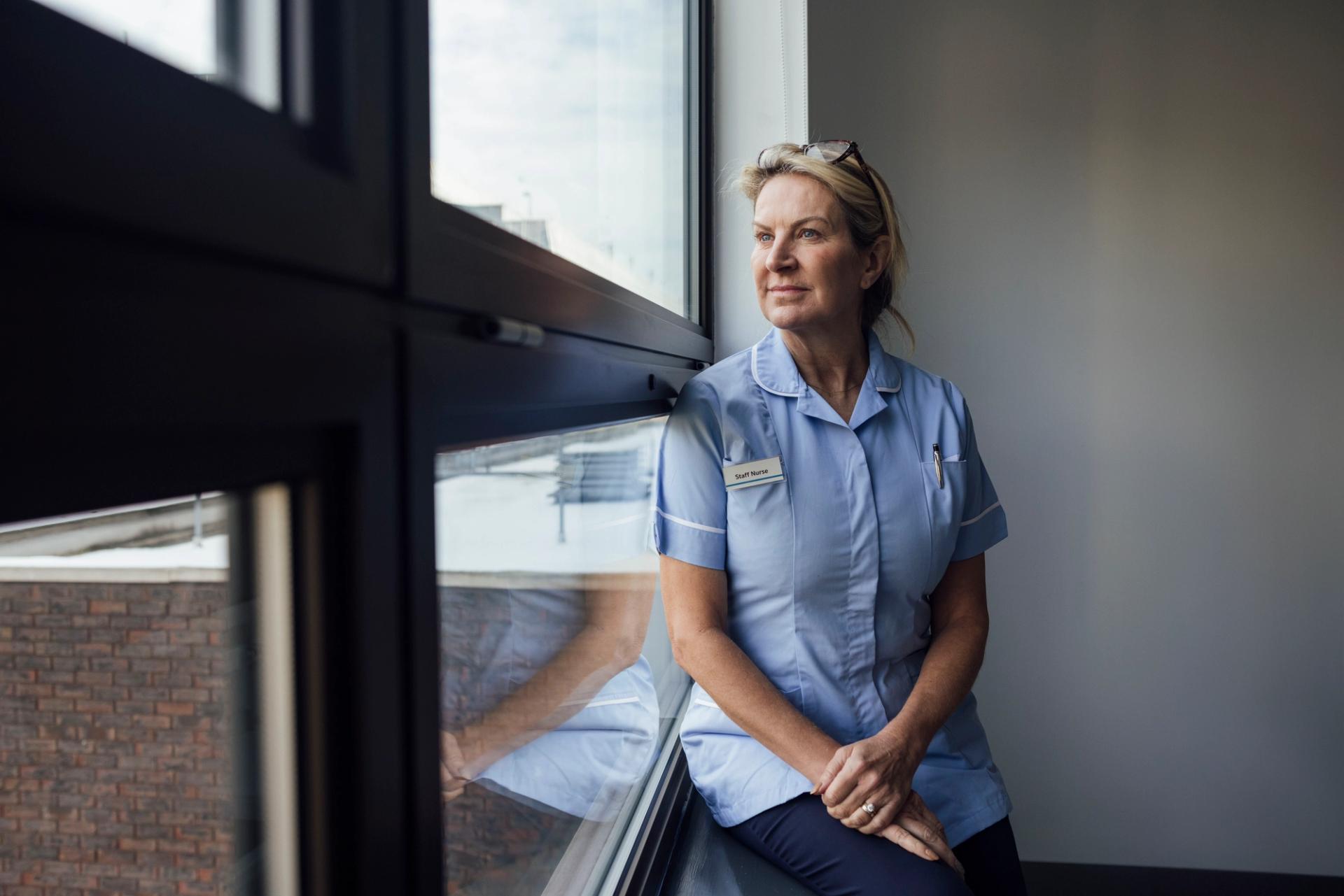 Female nurse in a blue uniform looking out the window