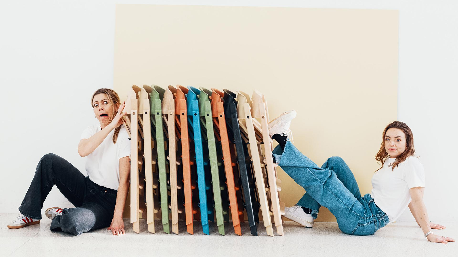 two women on either side of a stack of colourful folded high chairs