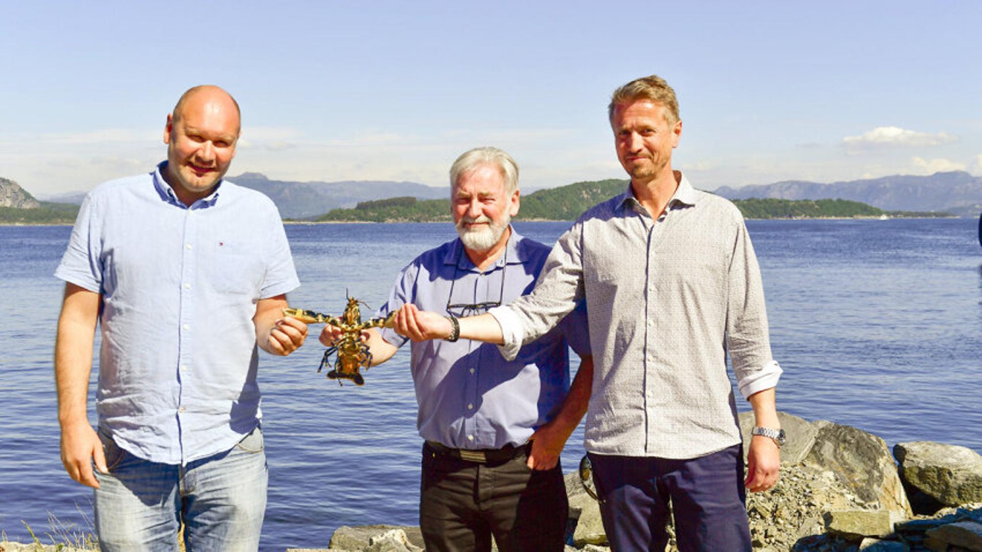 Three men holding lobster