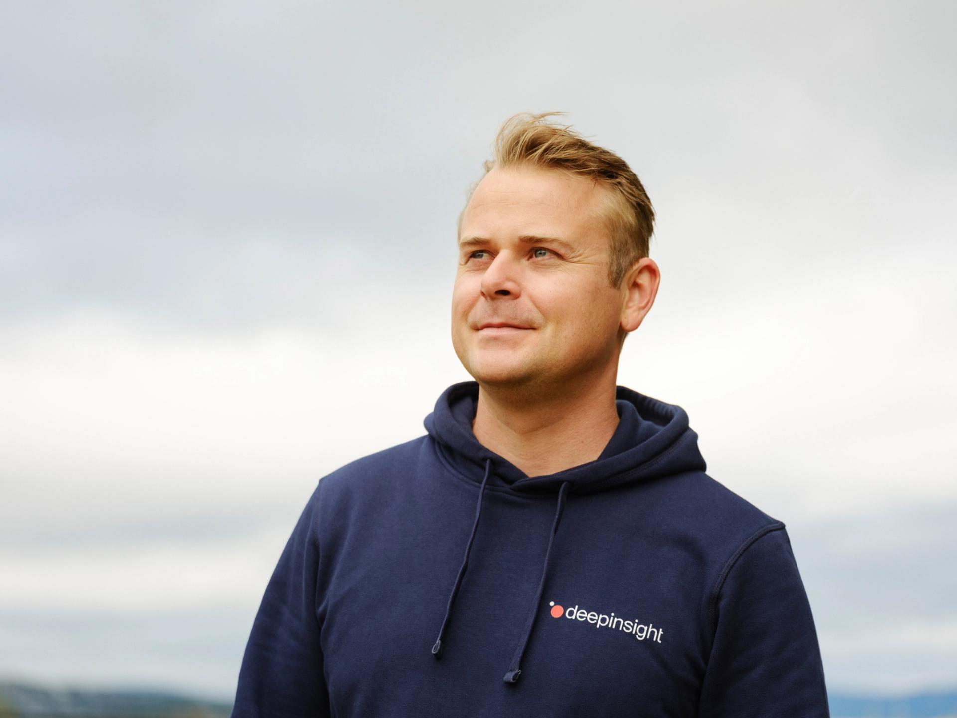 A man smiling, wearing a deep insight hoodie.