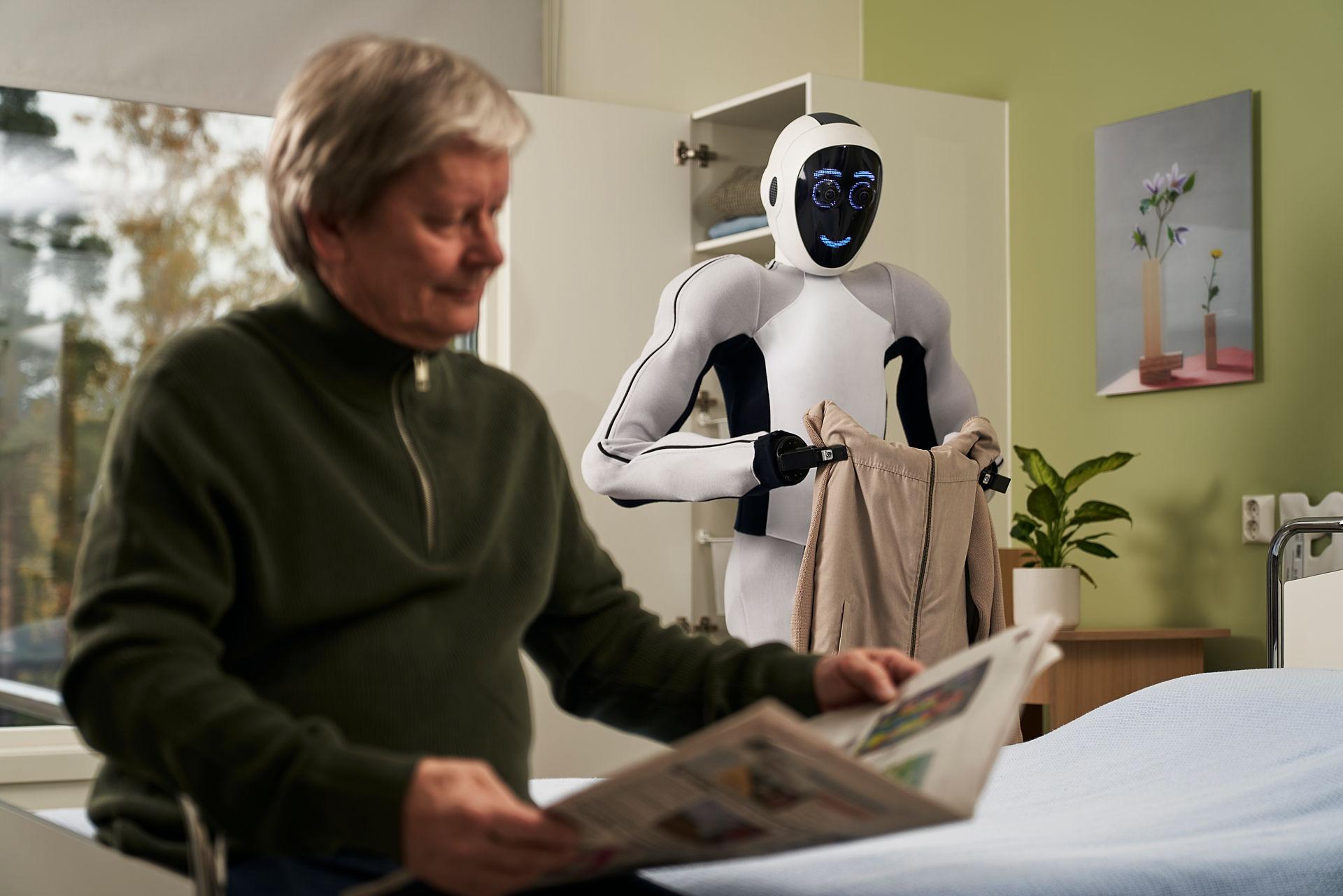 White humanoid robot folding clothes for a hospital patient
