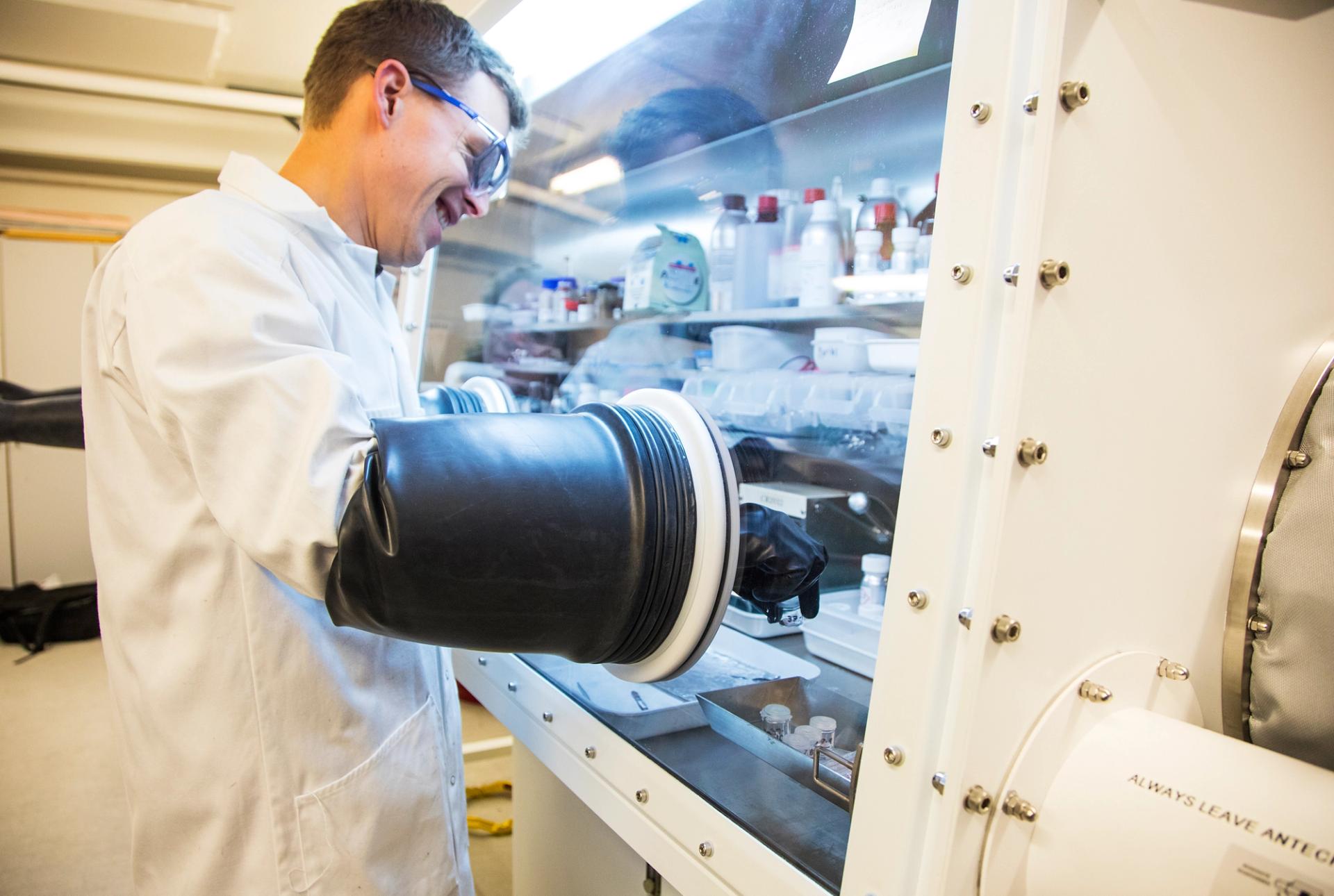 Man in a white lab coat and safety glasses with working in a clean room
