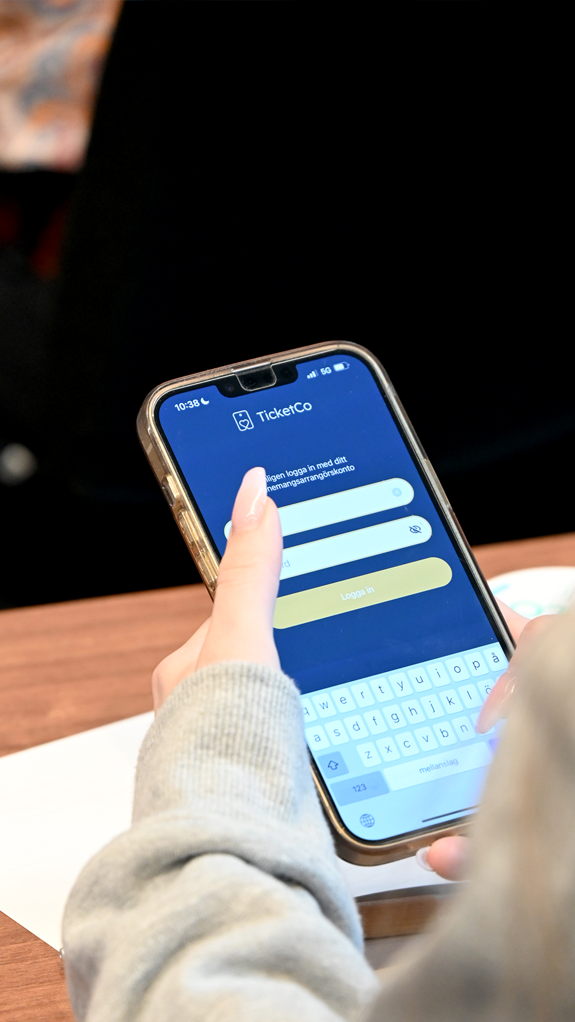 A woman with long nails looking at Ticketco on her iPhone.