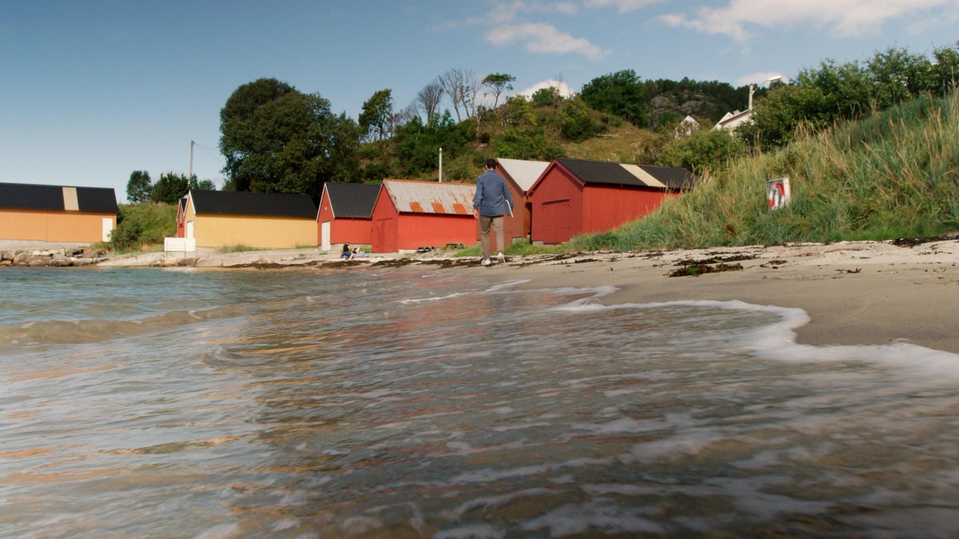 Red and yellow boat huts on the beach in Norway