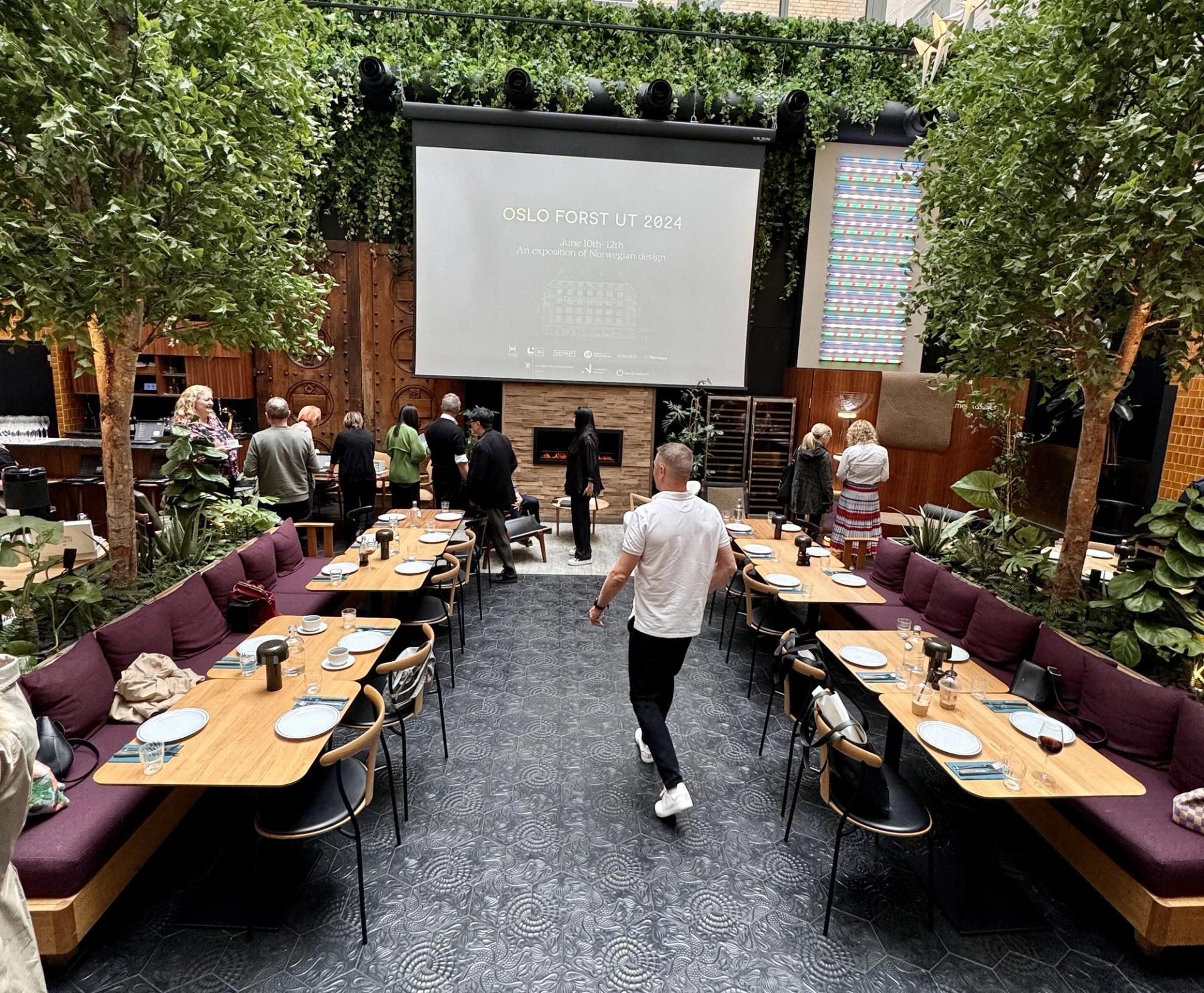 People at a conference indoors with trees and plum colored benches