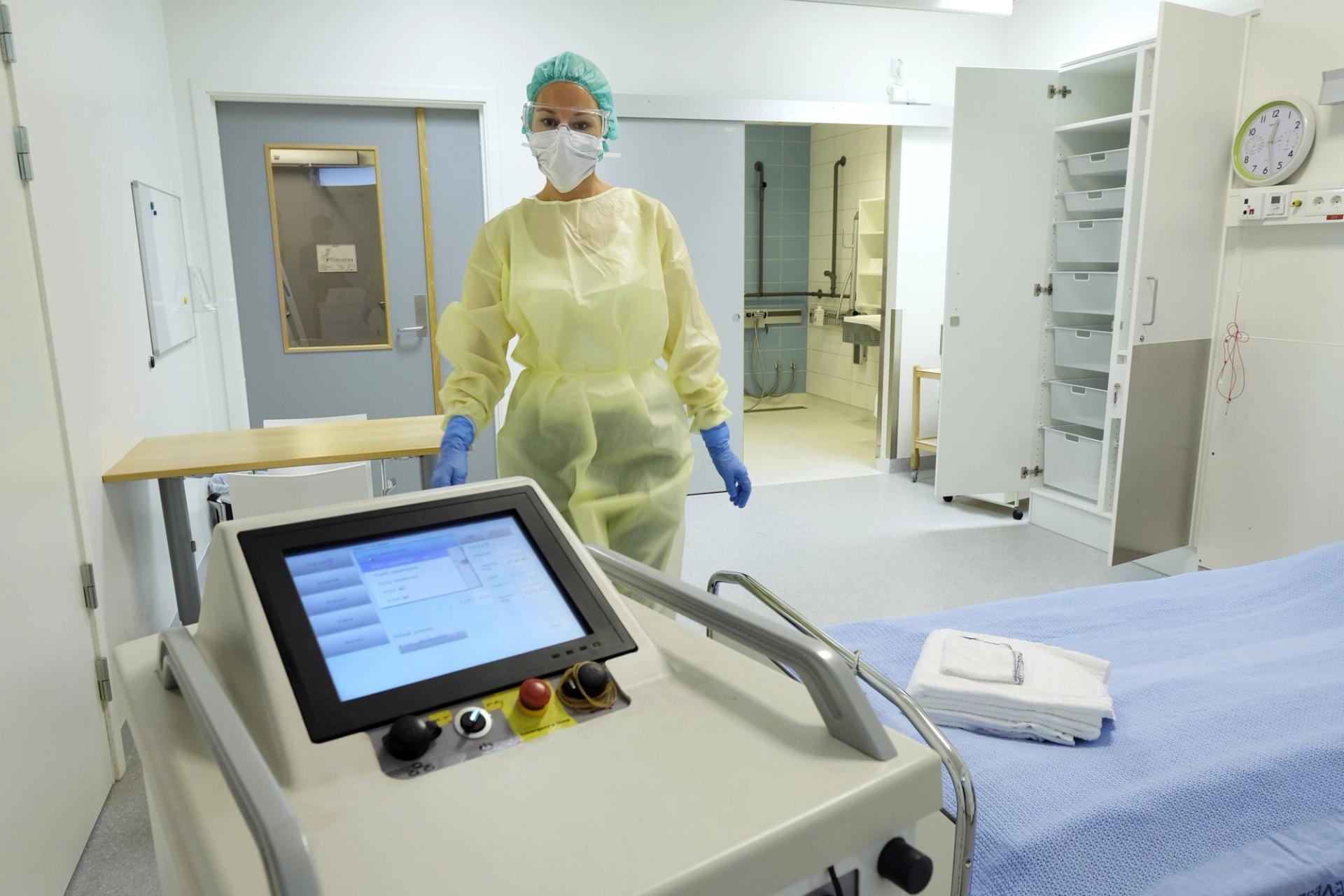 Hospital worker in protective gear using a disinfection robot