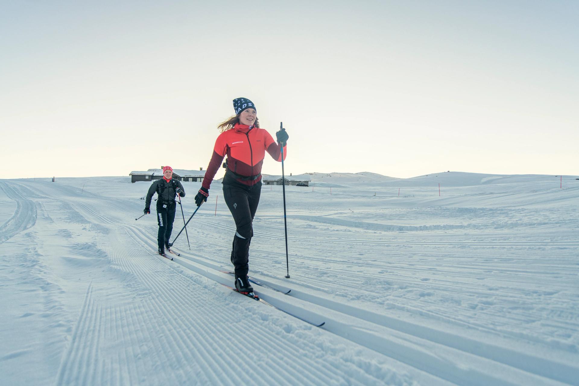 Woman in red jacket and blue hat cross country skiing