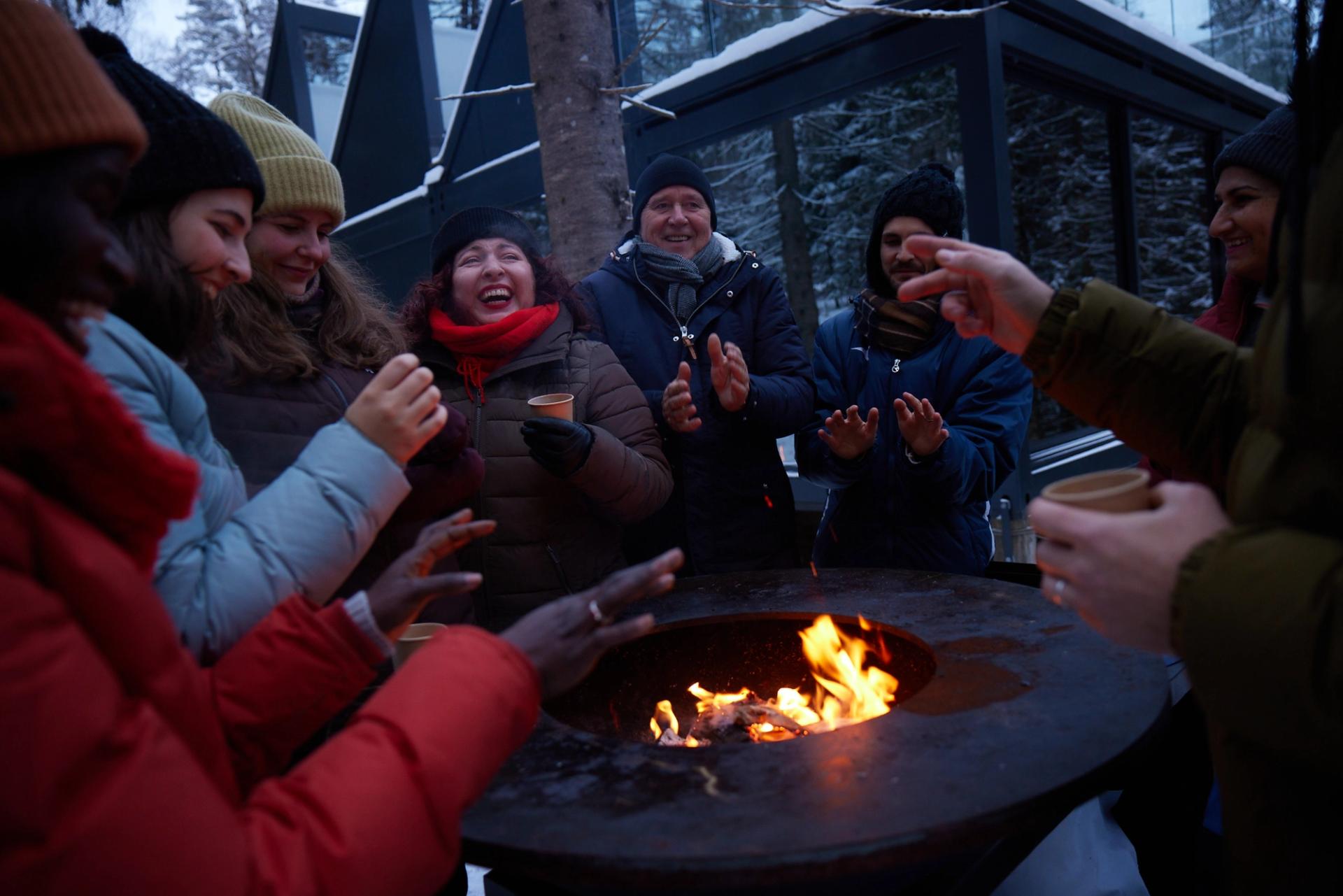 People in winter clothing around a fire pit