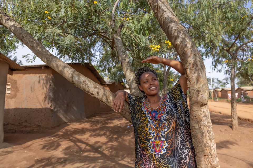 Woman leaning towards tree smiling