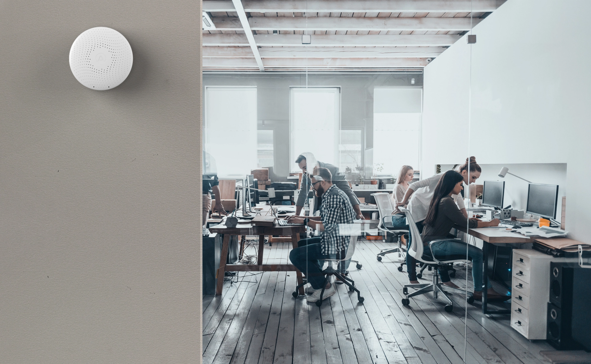 people working at their desks with an air sensor on the wall