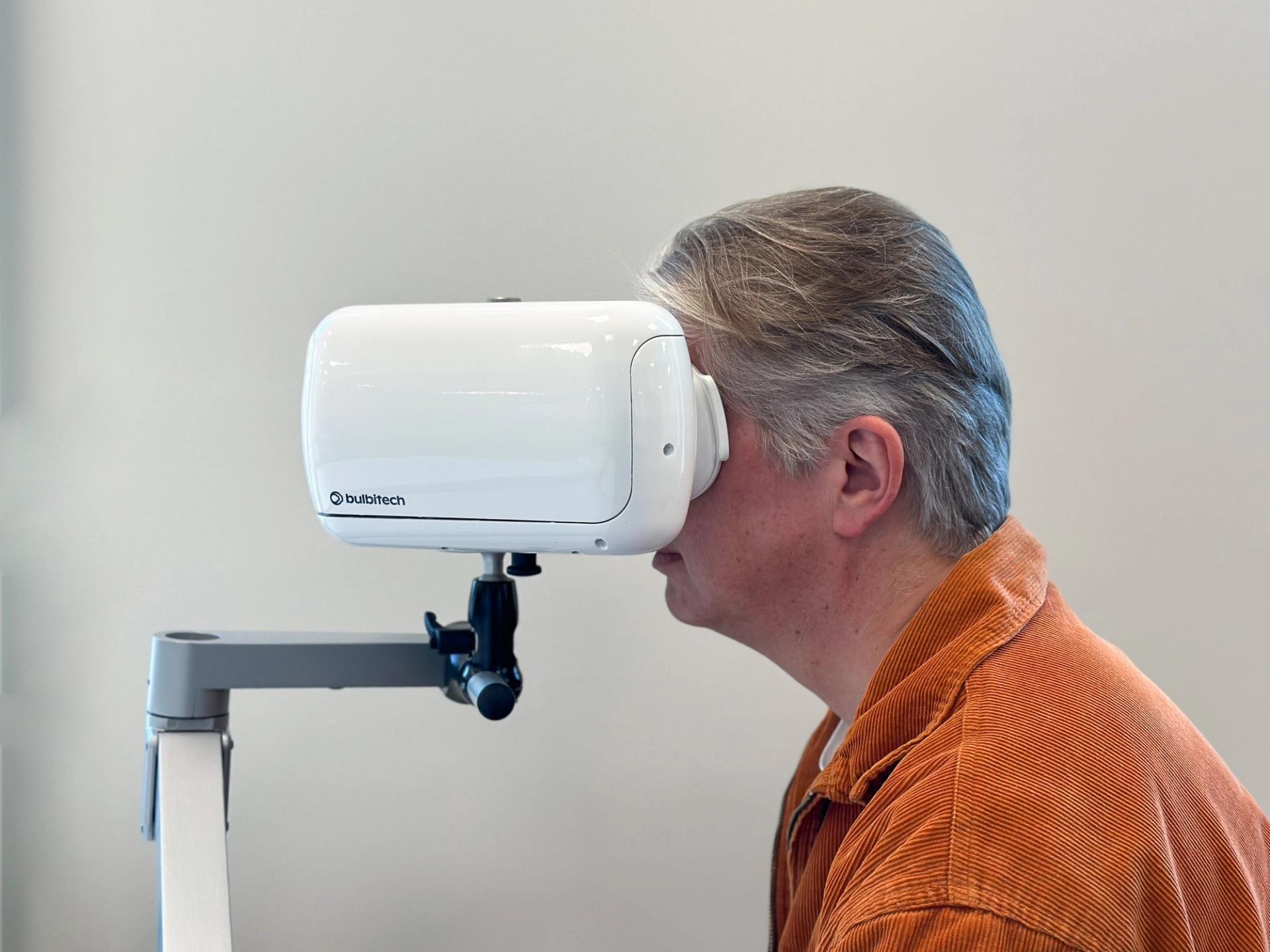 Older man in orange shirt looking into an eye-tracking camera