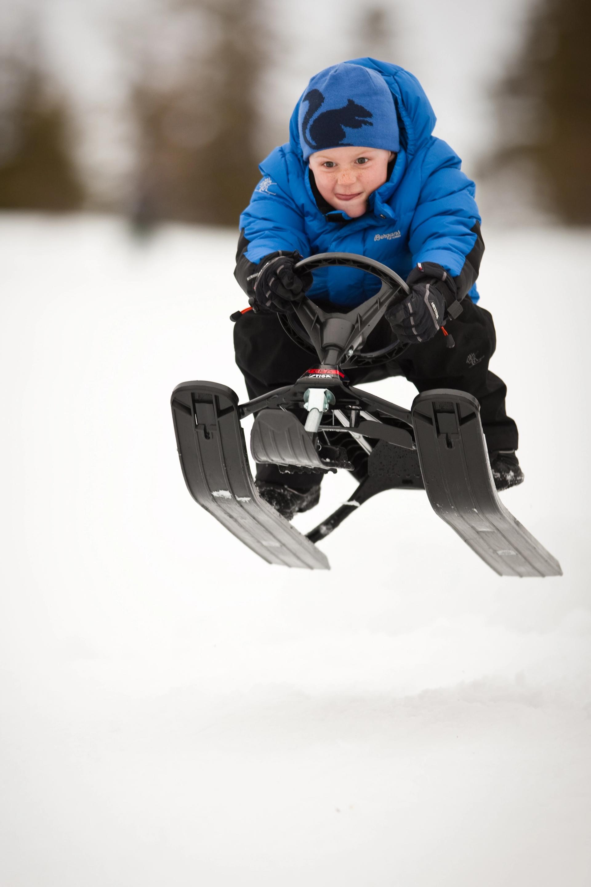 Boy in blue clothes racing on a black sled at Blefjell, Norway