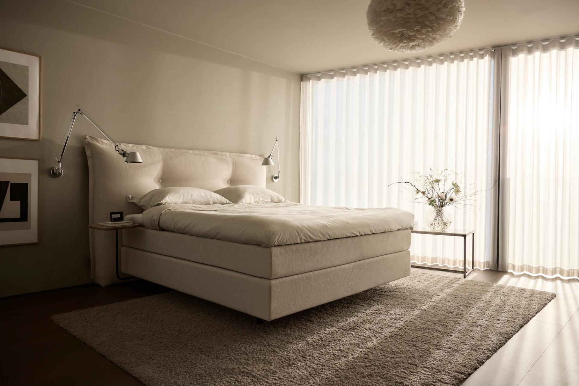 A bed in a bedroom, beige and light colors.