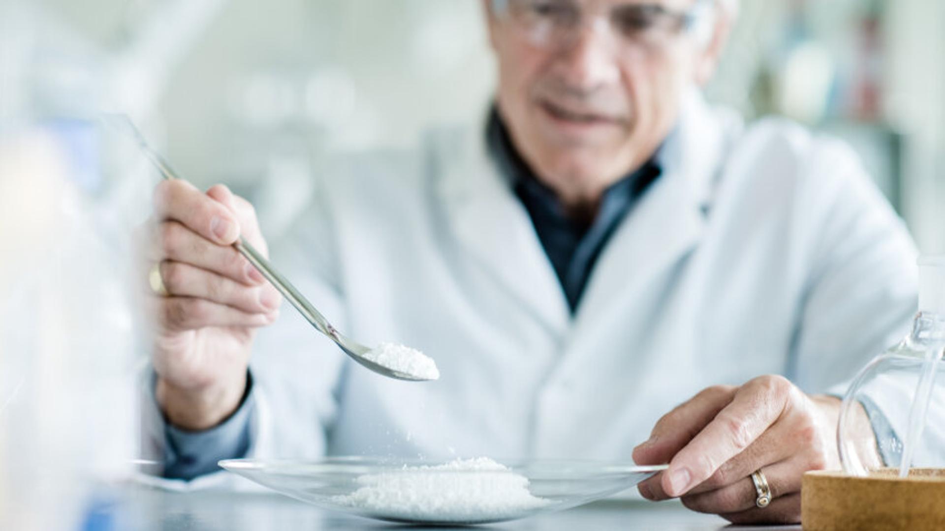 Man in a white lab coat measuring out powdered vanillin