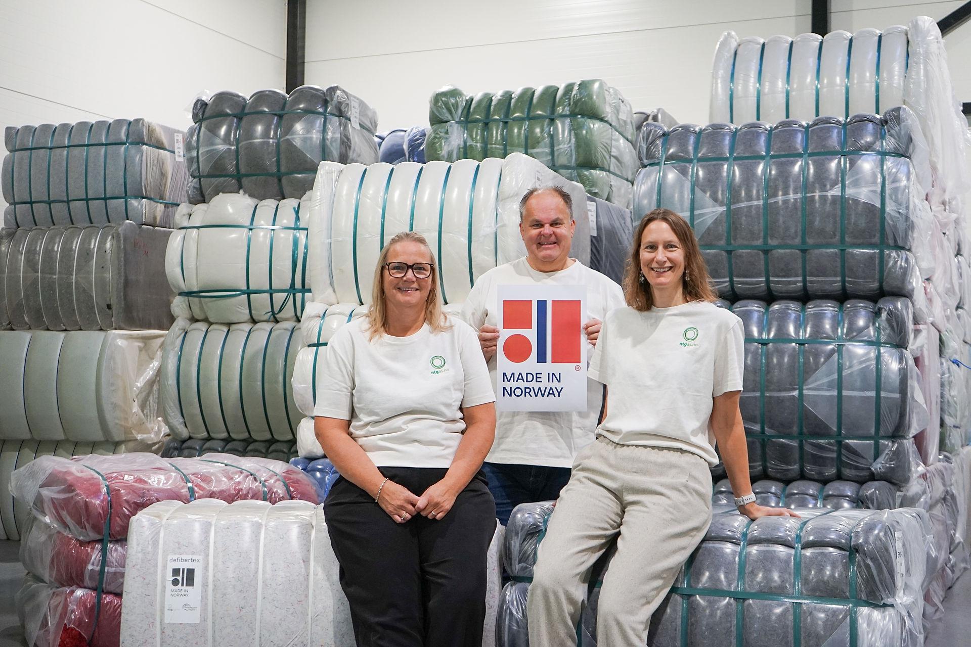 Three happy employees smiling to the camera, while sitting on recycled textile.