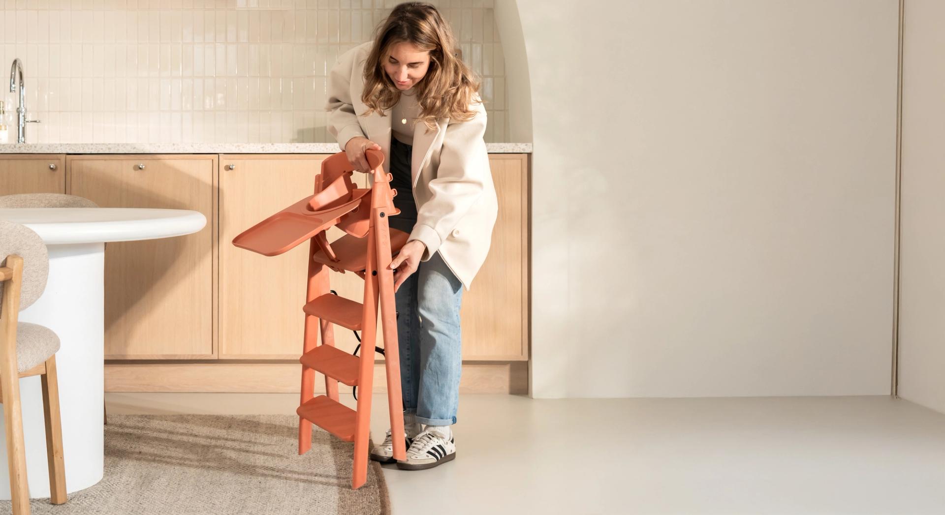 woman opening a folded orange high chair