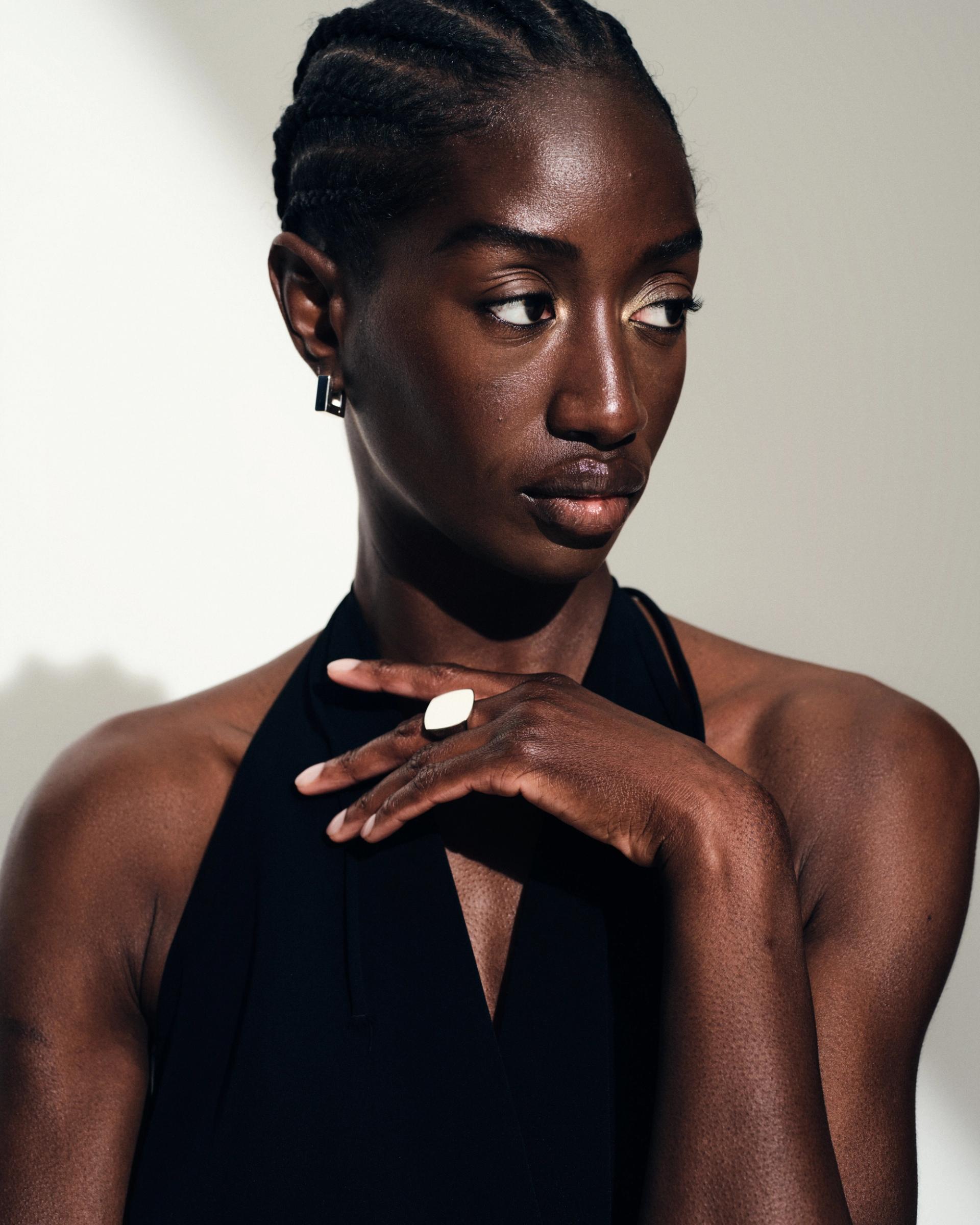 Woman with braids wearing a large square ring and small square hoop earrings