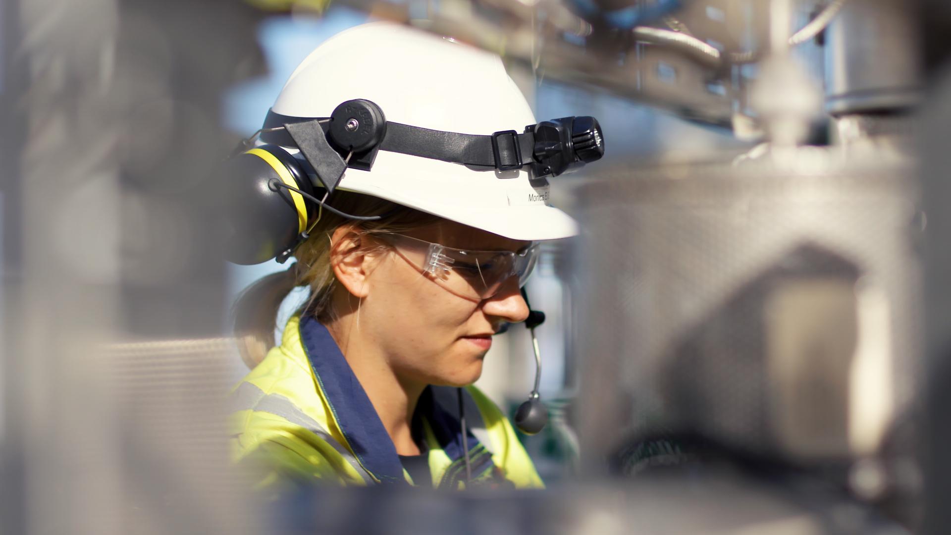 Woman in a white hard hat working at a carbon capture testing centre