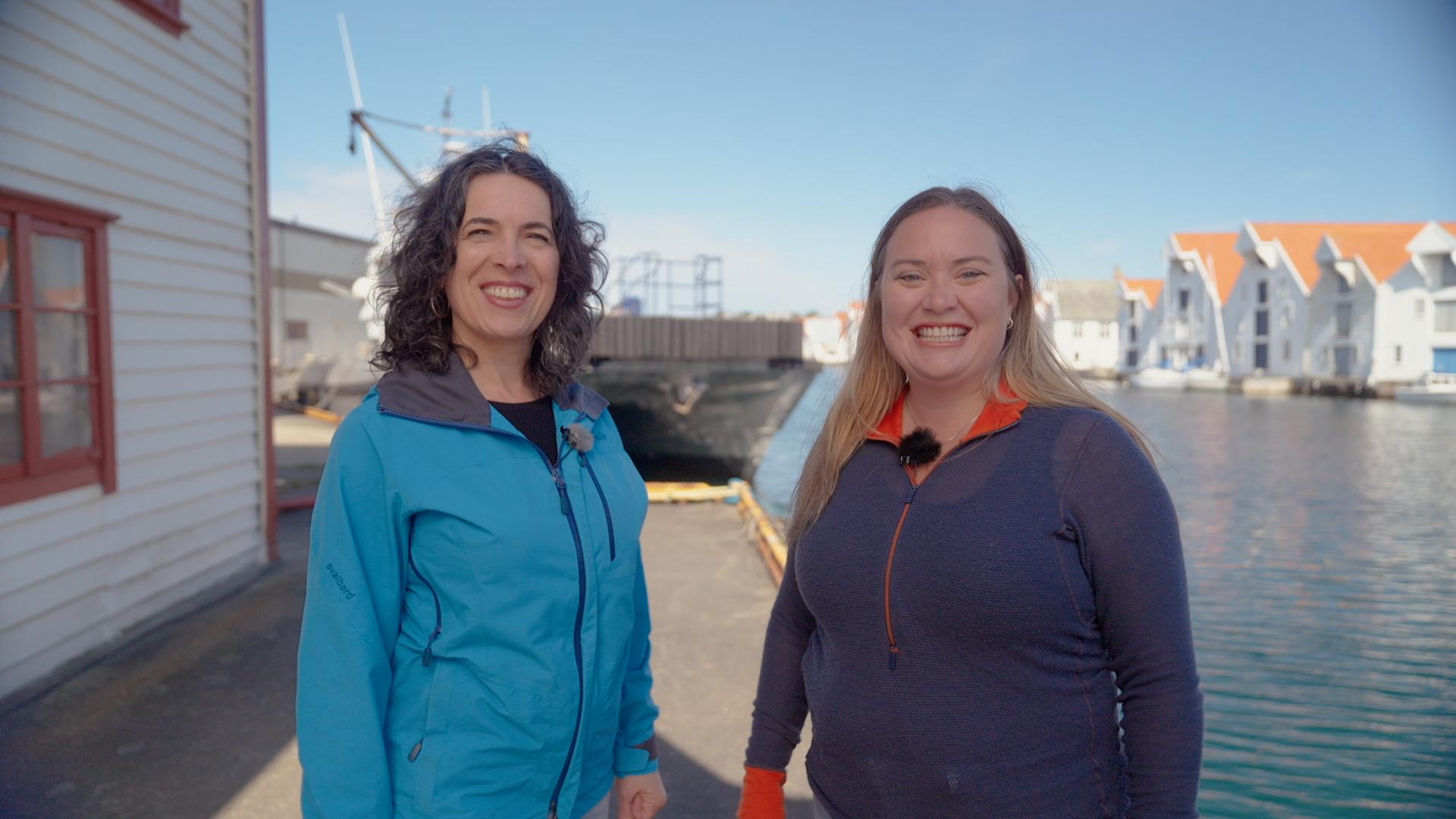 Two women in blue jackets on a wharf
