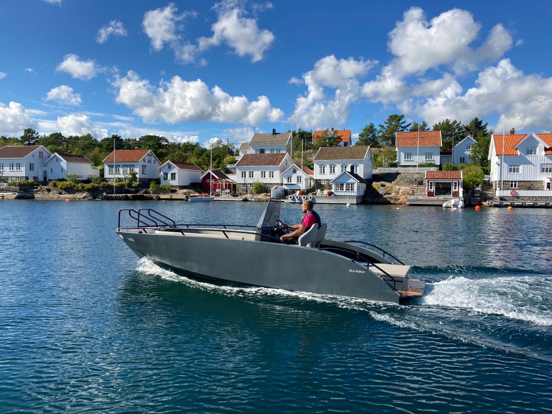 A small electric boat driving in front of old white houses