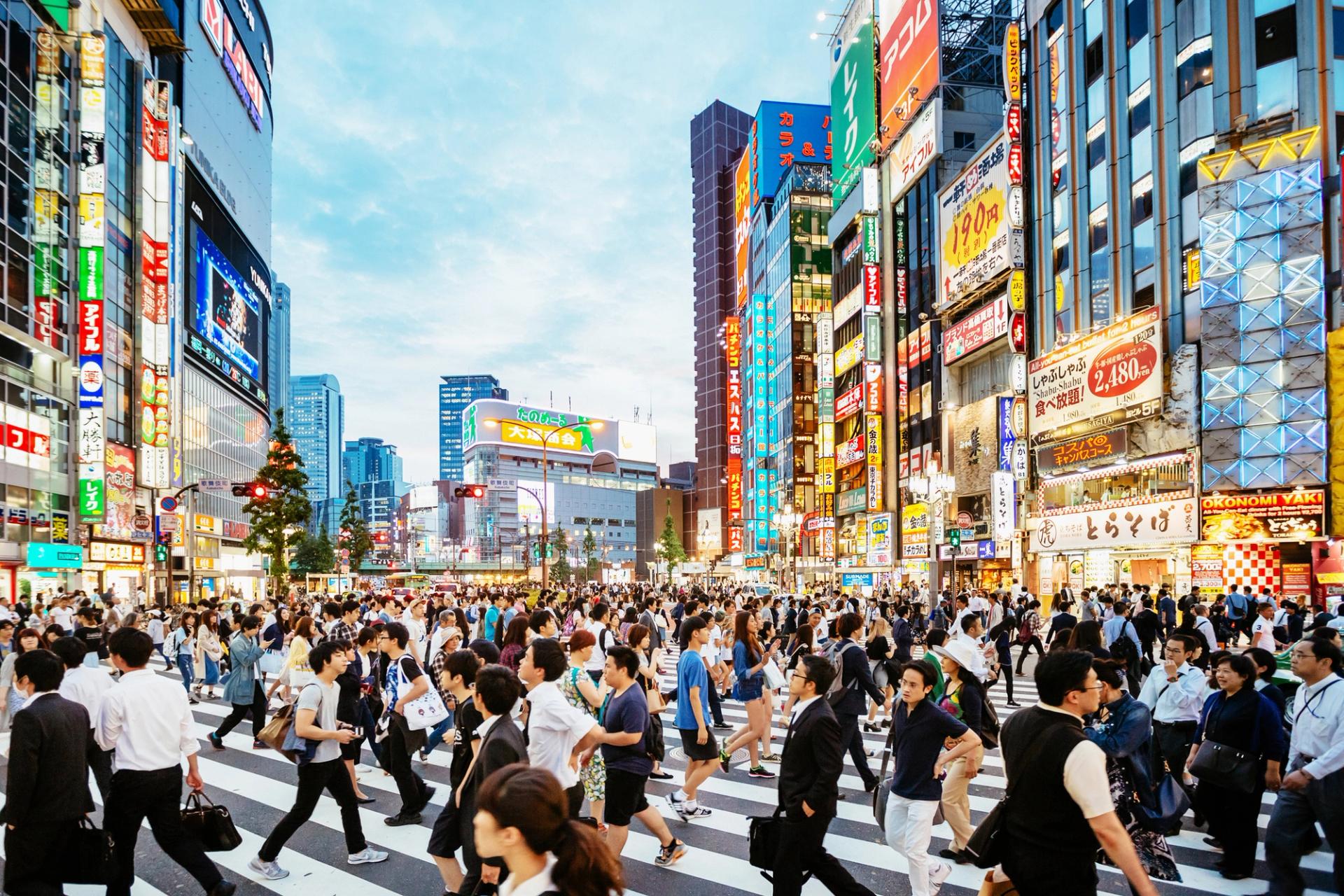 A crowded crosswalk in a japanese city surrounded by skyscrapers