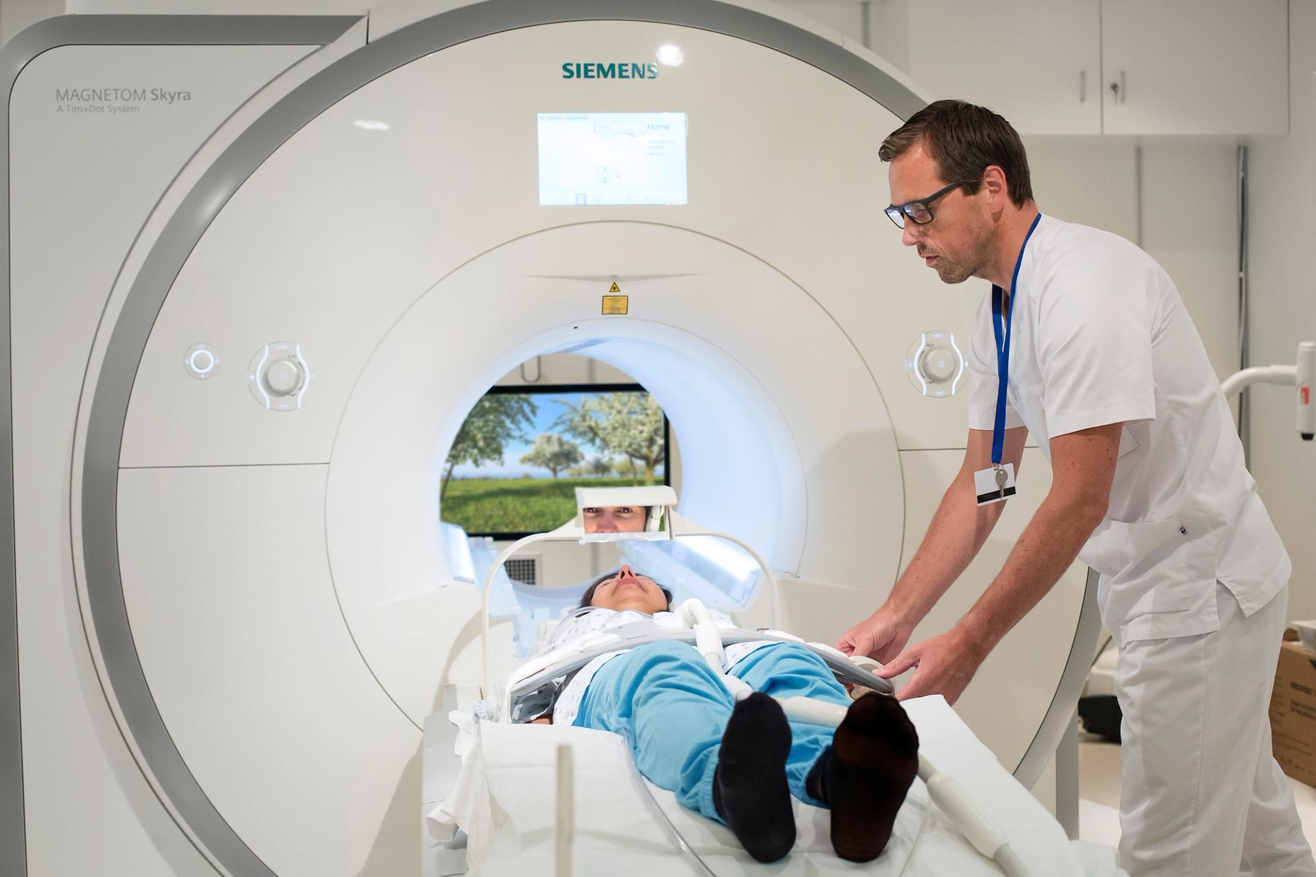Lab technician guiding a person into an MRI machine