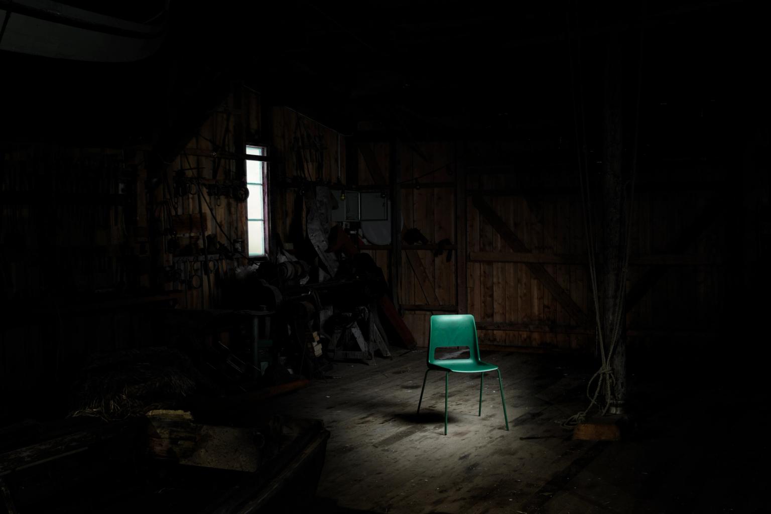 Green plastic chair with metal legs against a dark background