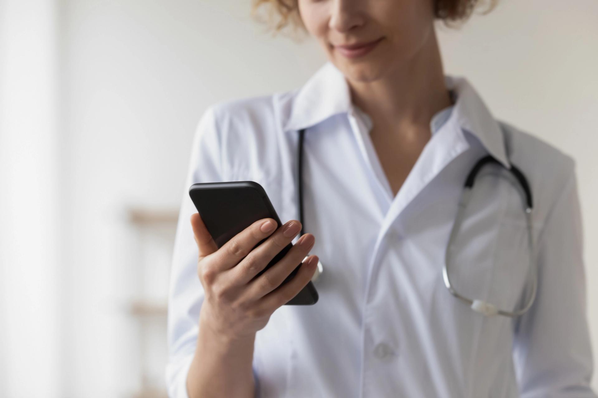 Woman in lab coat looking at a smartphone