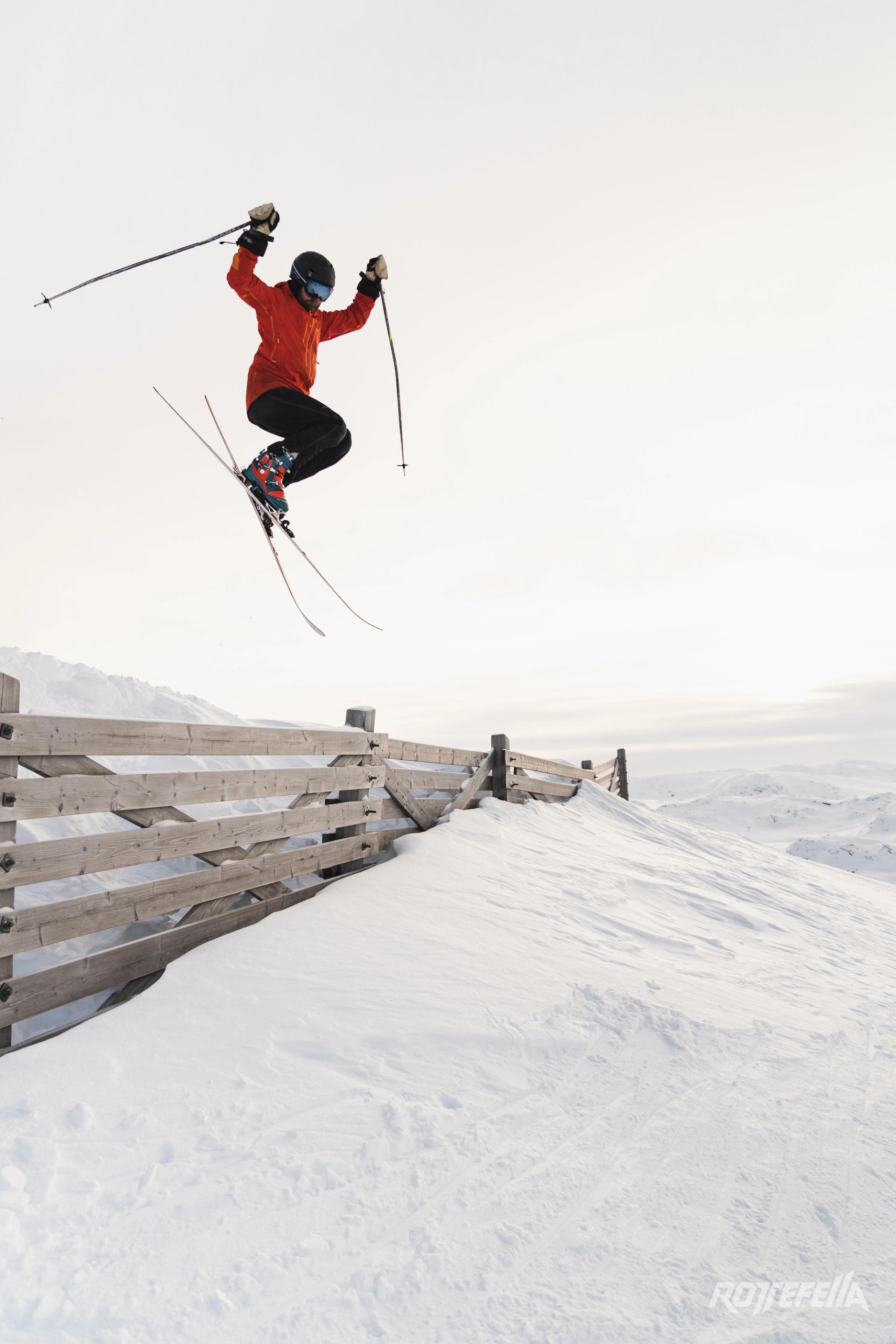 skier jumping over a wooden fence