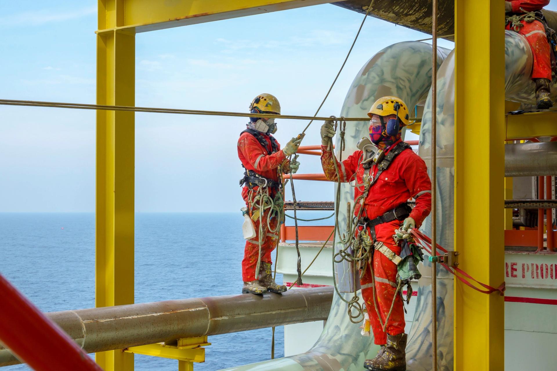 Two men in safety gear working at the top of an offshore wind turbine