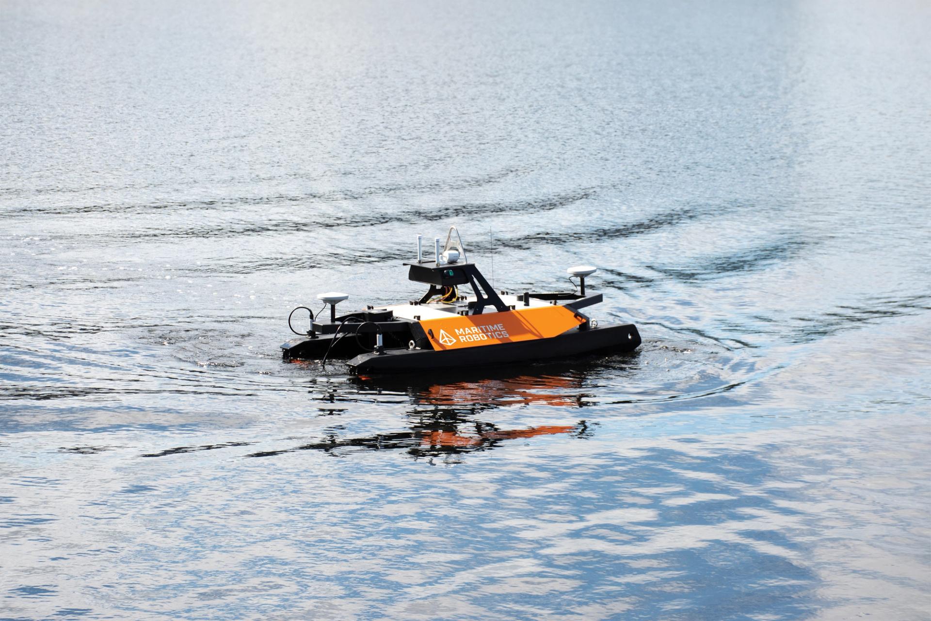 small orange uncrewed surface vehicle sailing in calm water