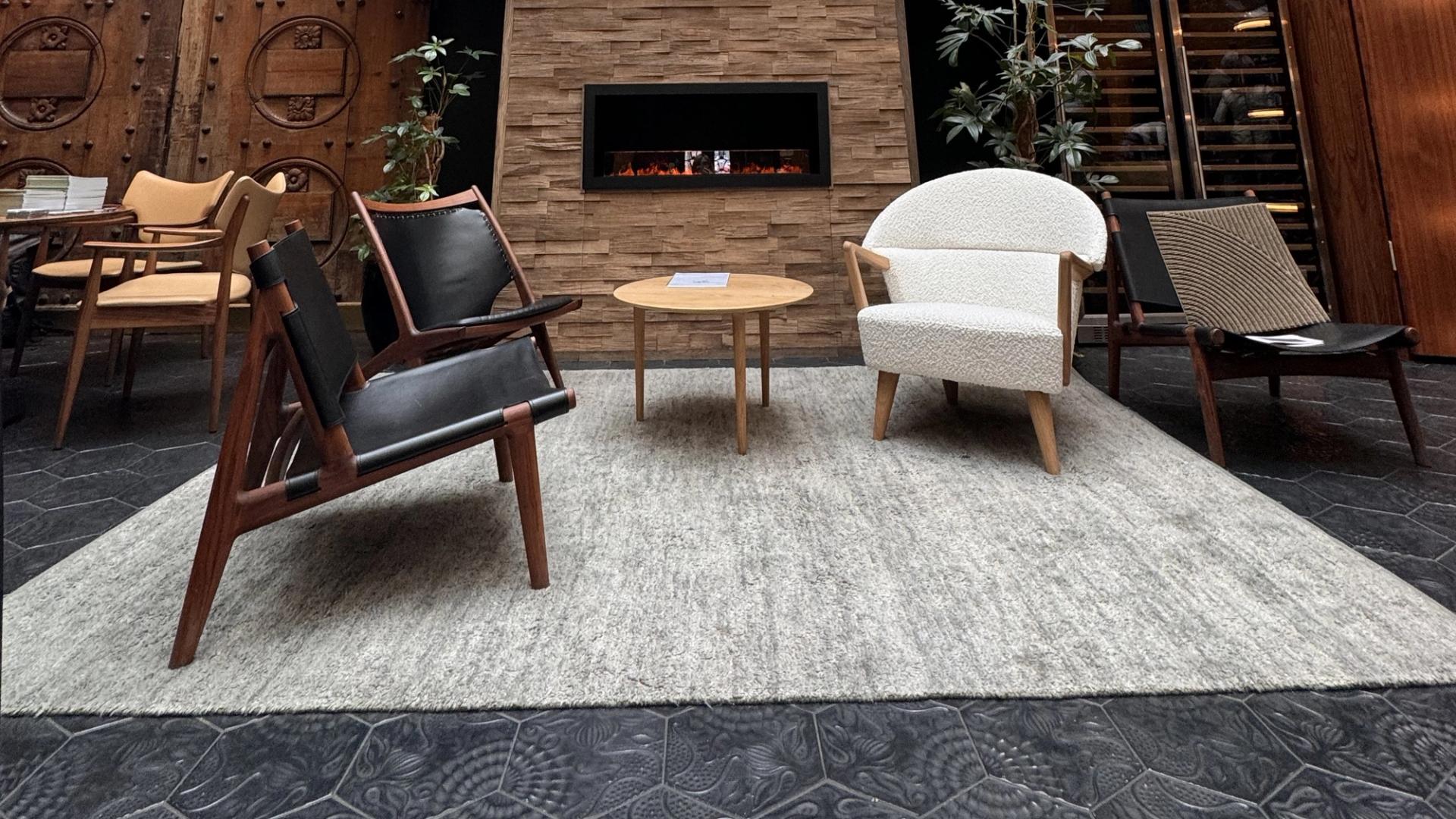 Two black leather chairs and one white leather chair in front of a fireplace