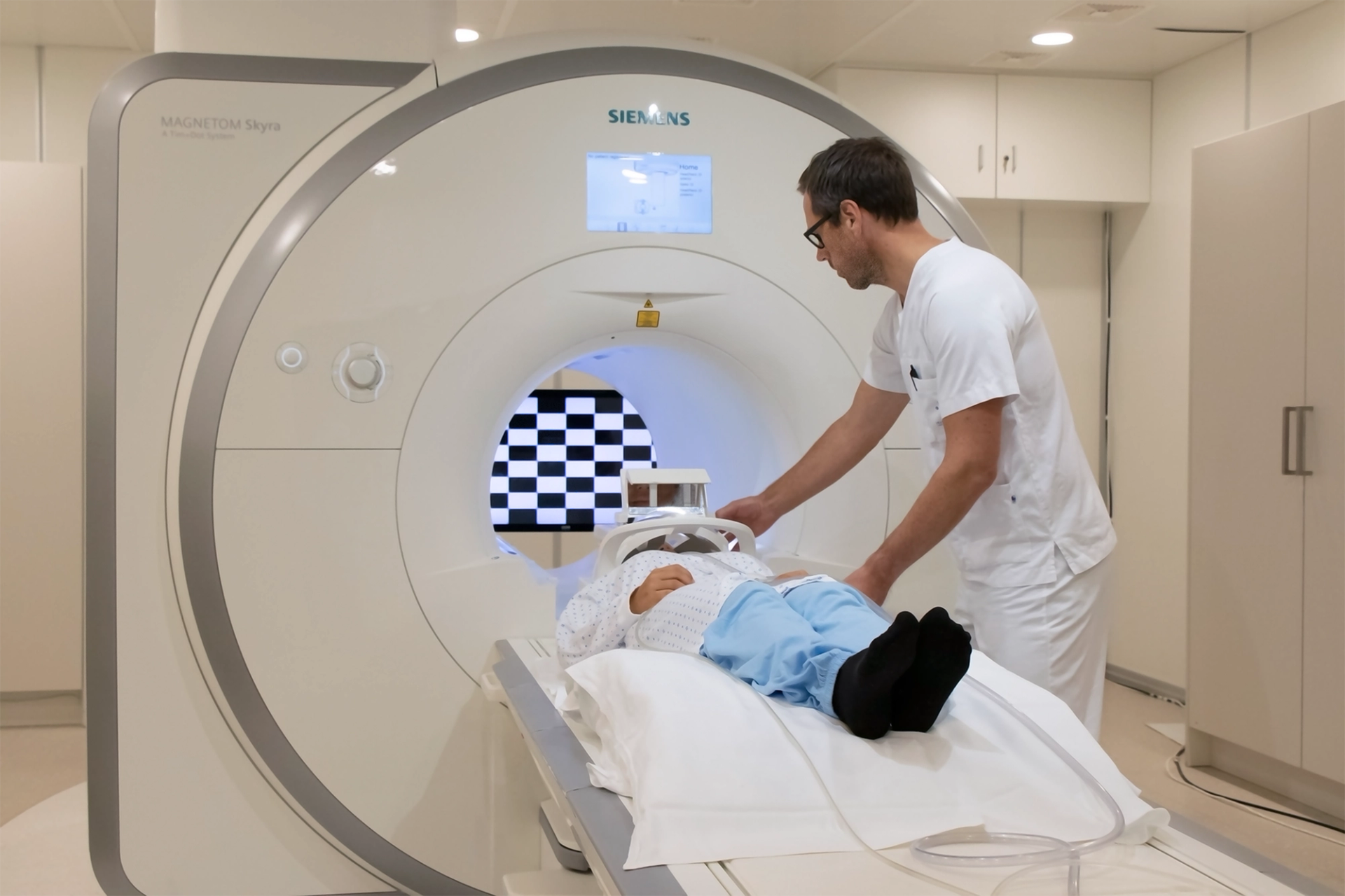 Lab technician guiding a person into an MRI machine