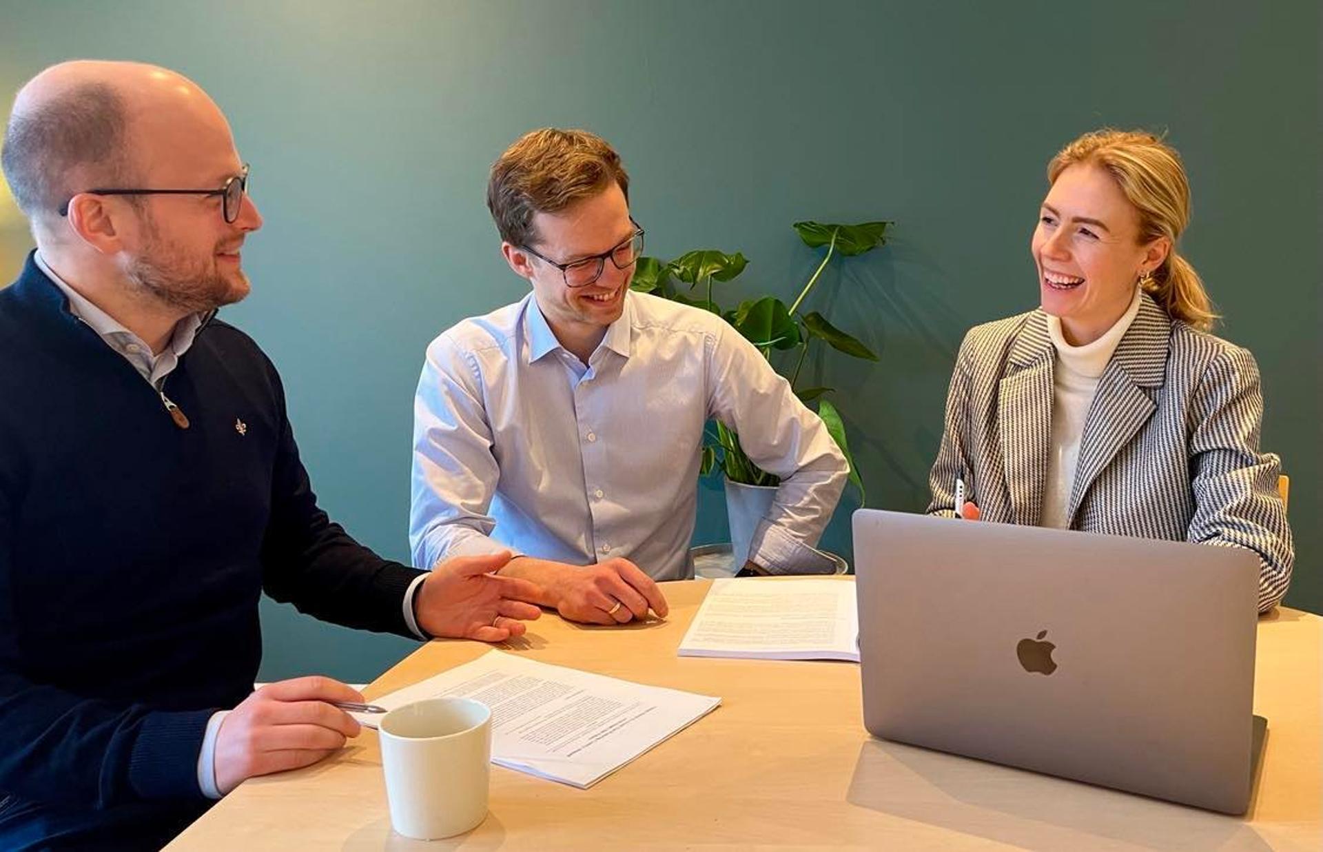 Two men and a woman sitting and smiling at a table