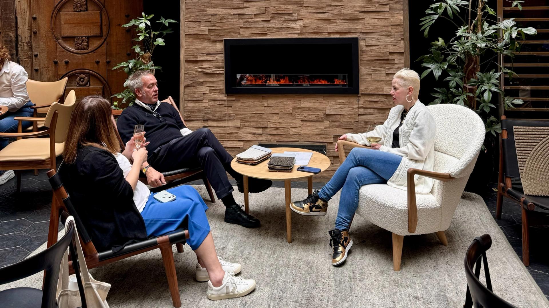 Three people chatting in front of a fireplace