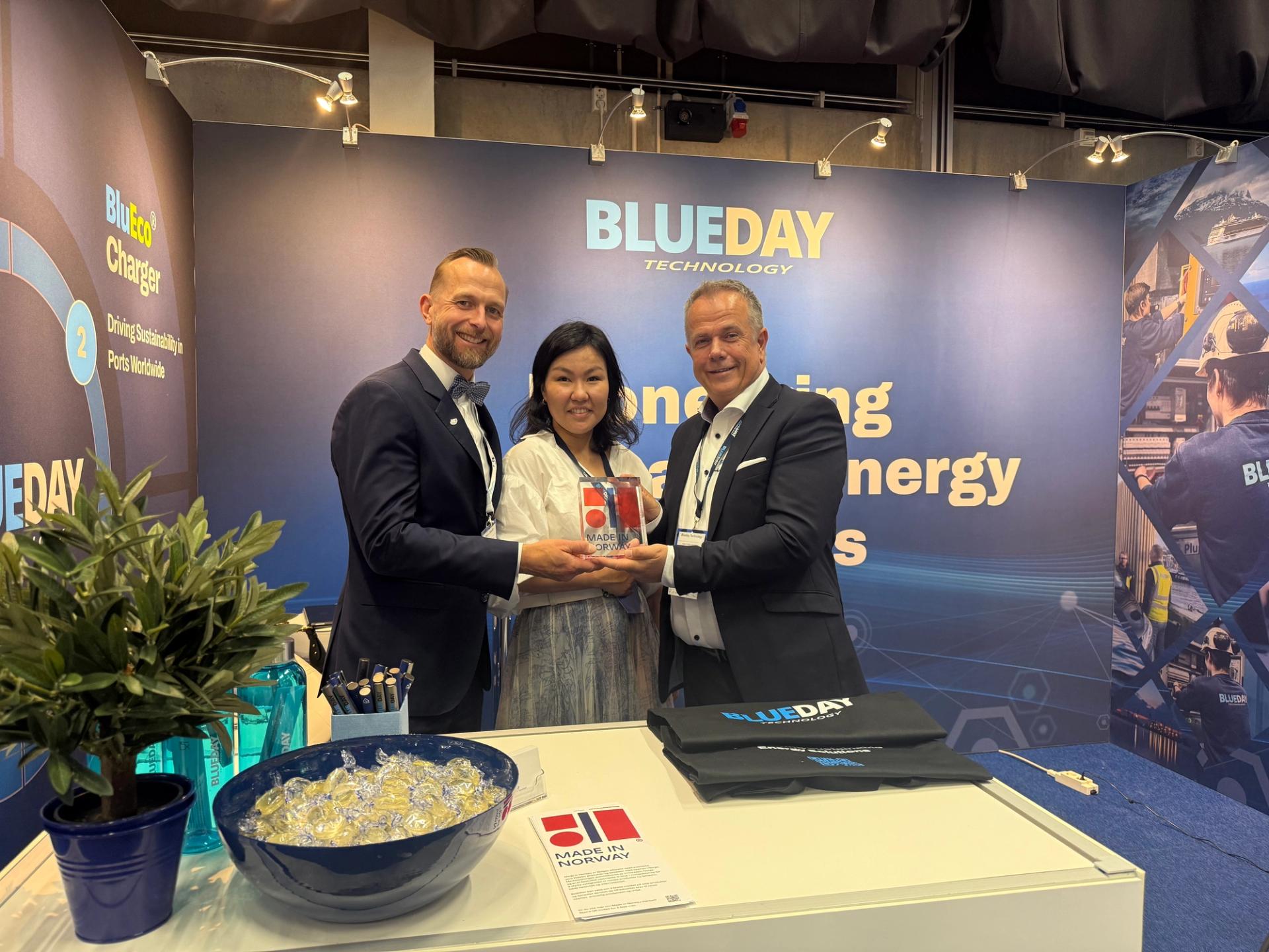 3 people holding a Made in Norway statue and smiling to the camera