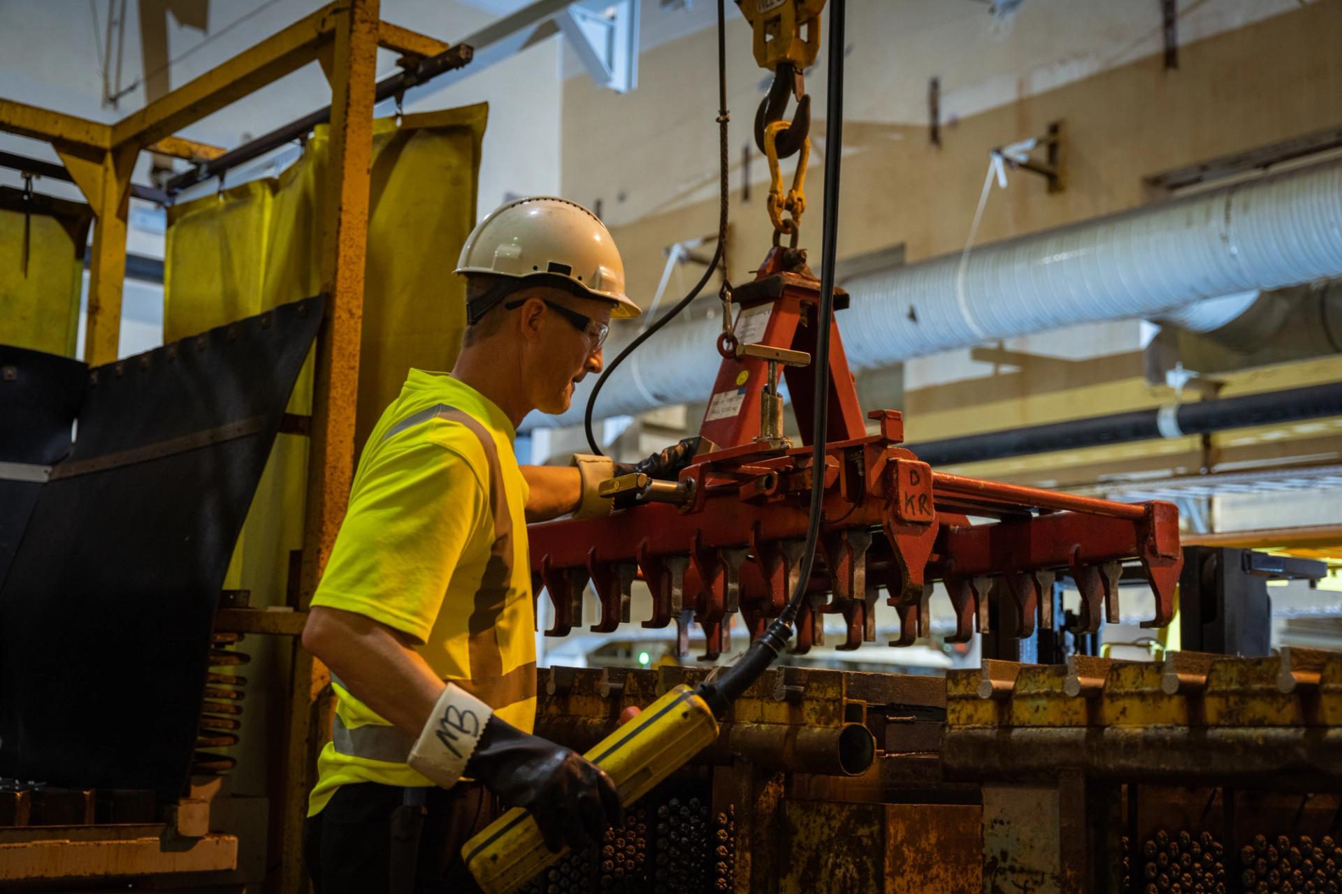 Worker in a hard hat moving nickel plates in a nickel/mineral refinery