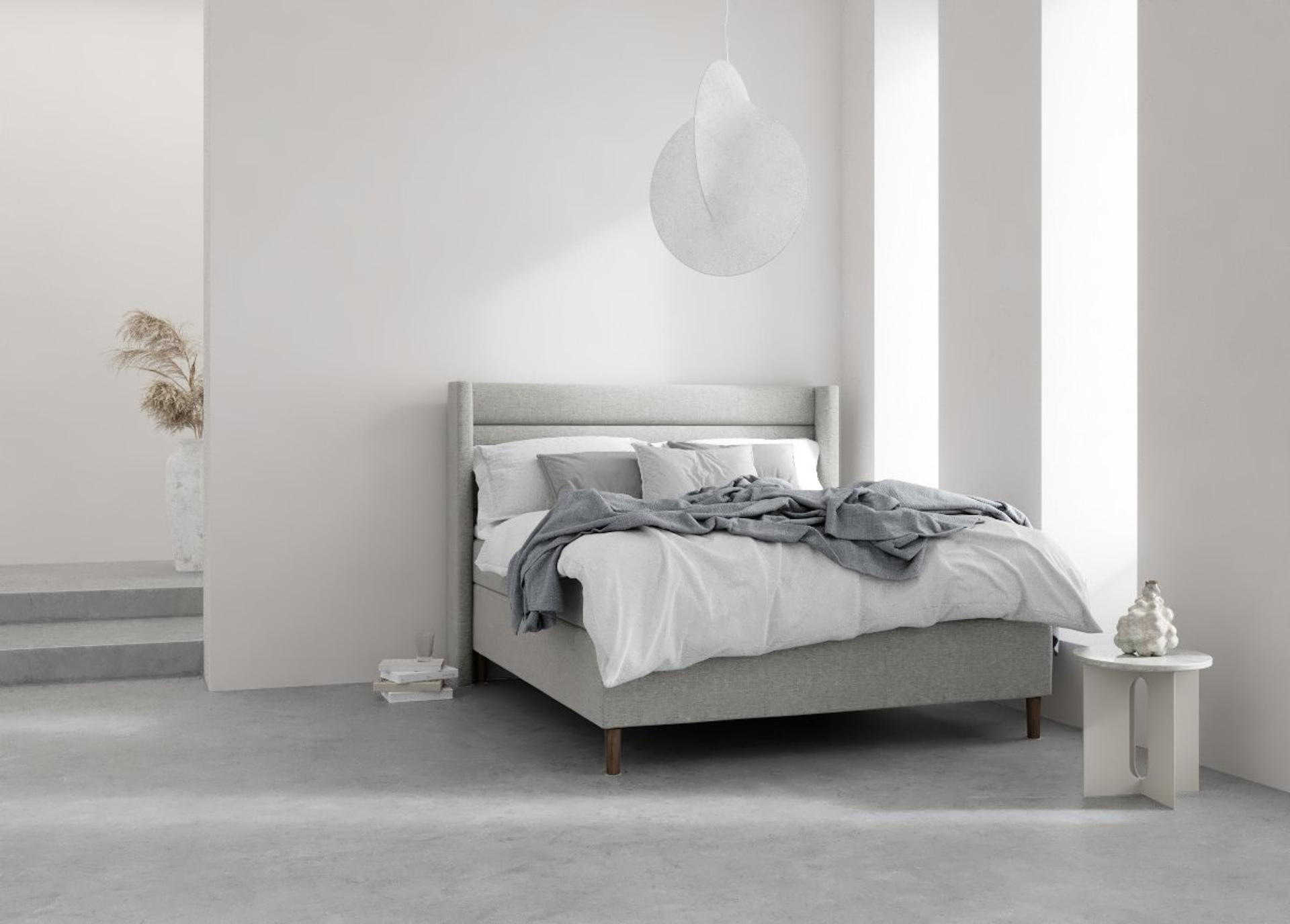 A grey bed in a clean and white room.