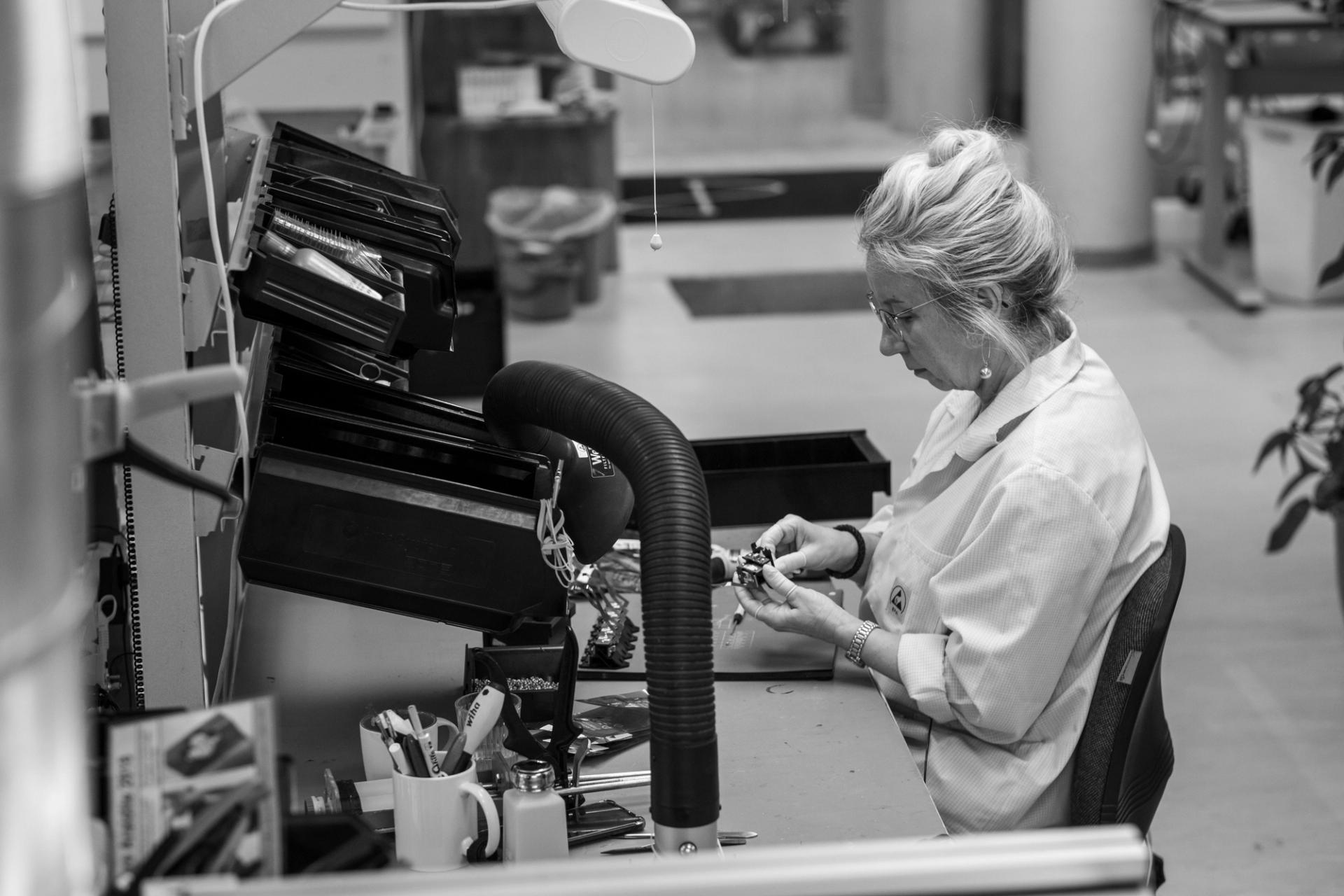Woman assembling optronic equipment at a workbench