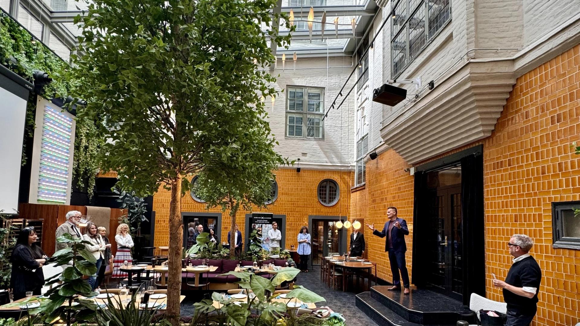 Man welcoming a group of people in front of an orange tiled building